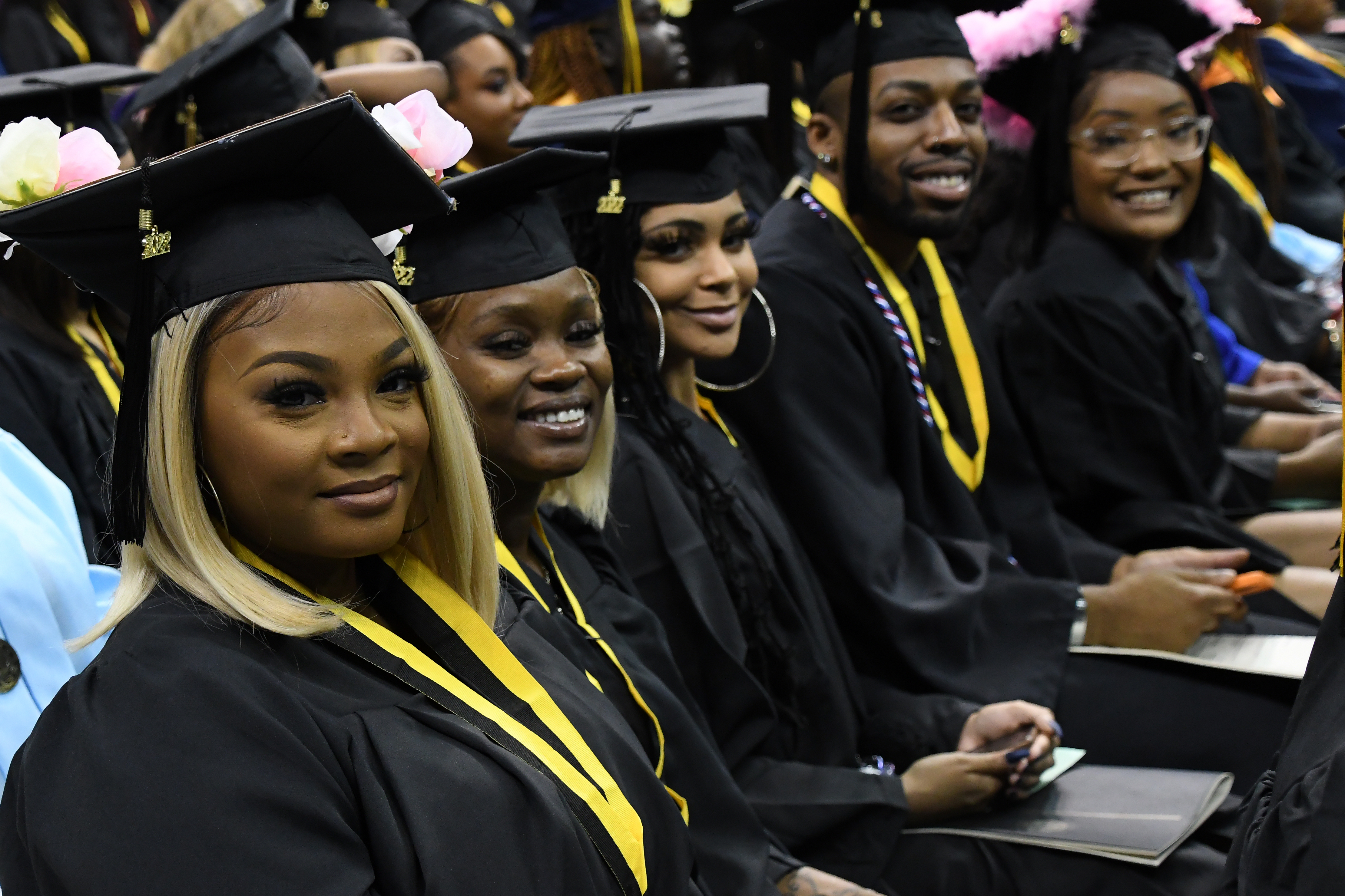 A row of graduates sitting together smile at the camera.
