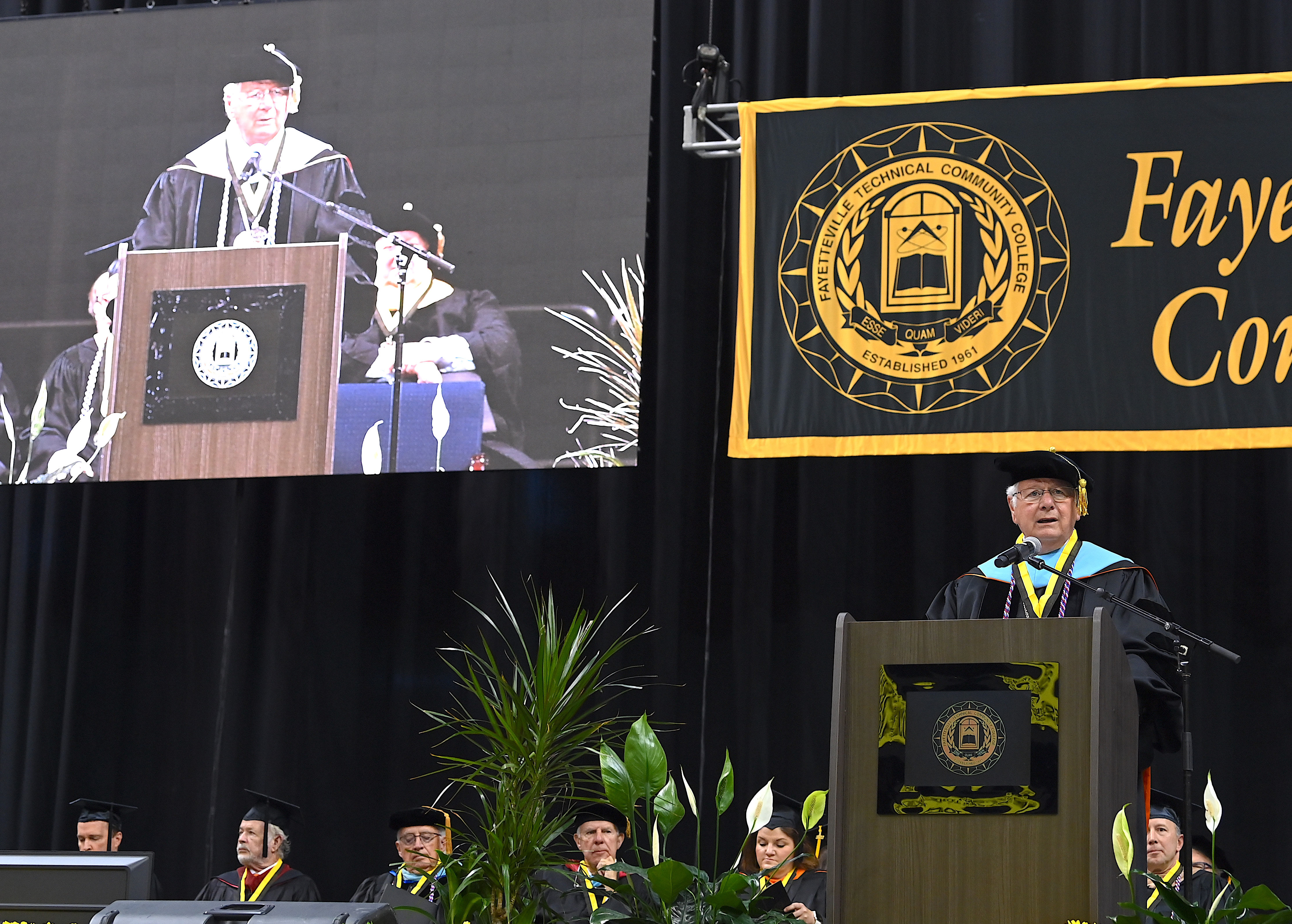 Dr. Keen is visible in the foreground speaking at the podium. The video display of him speaking is visible in the background.