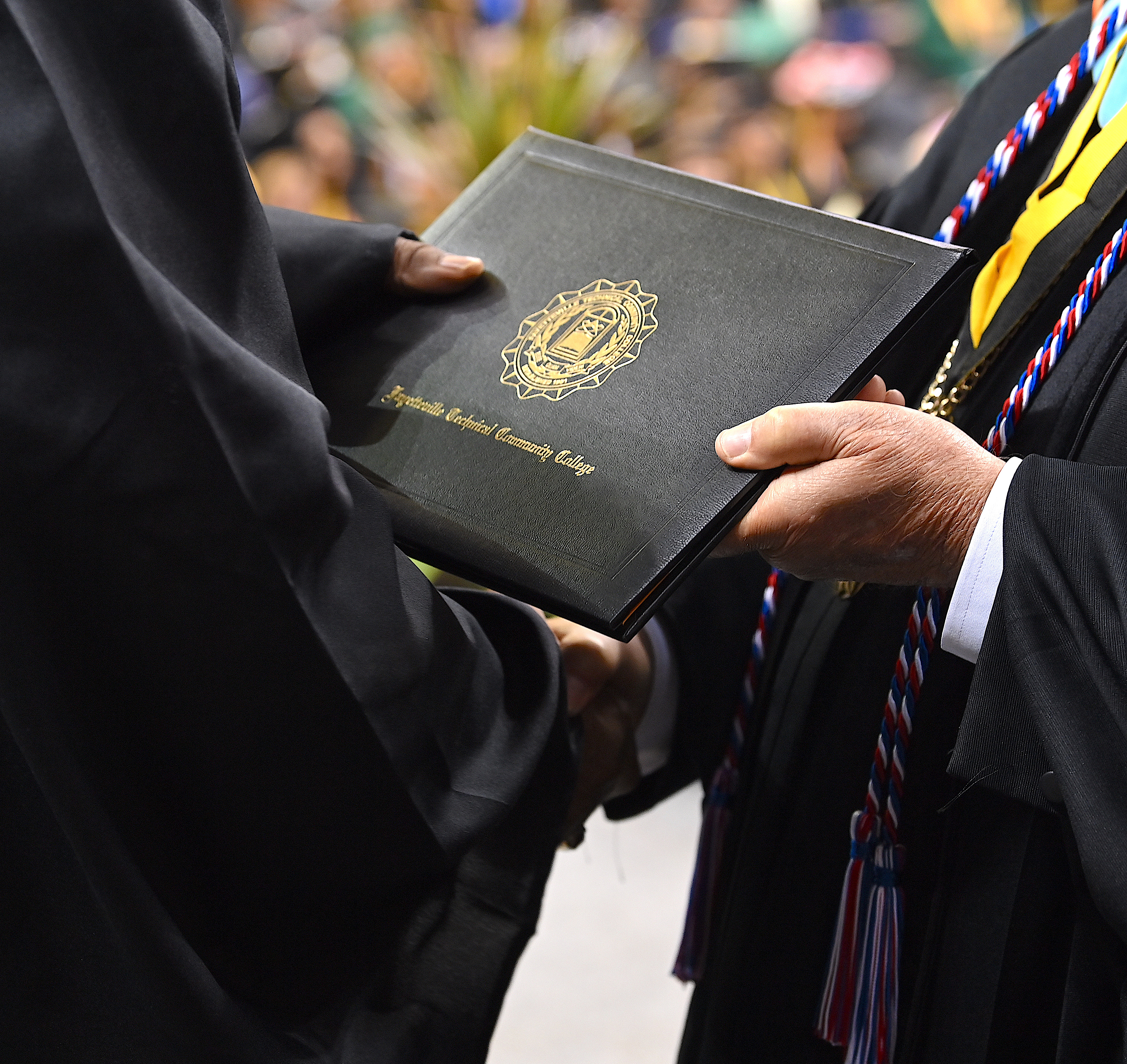 A close up of a degree portfolio as it is being passed from Dr. Keen to a graduate.
