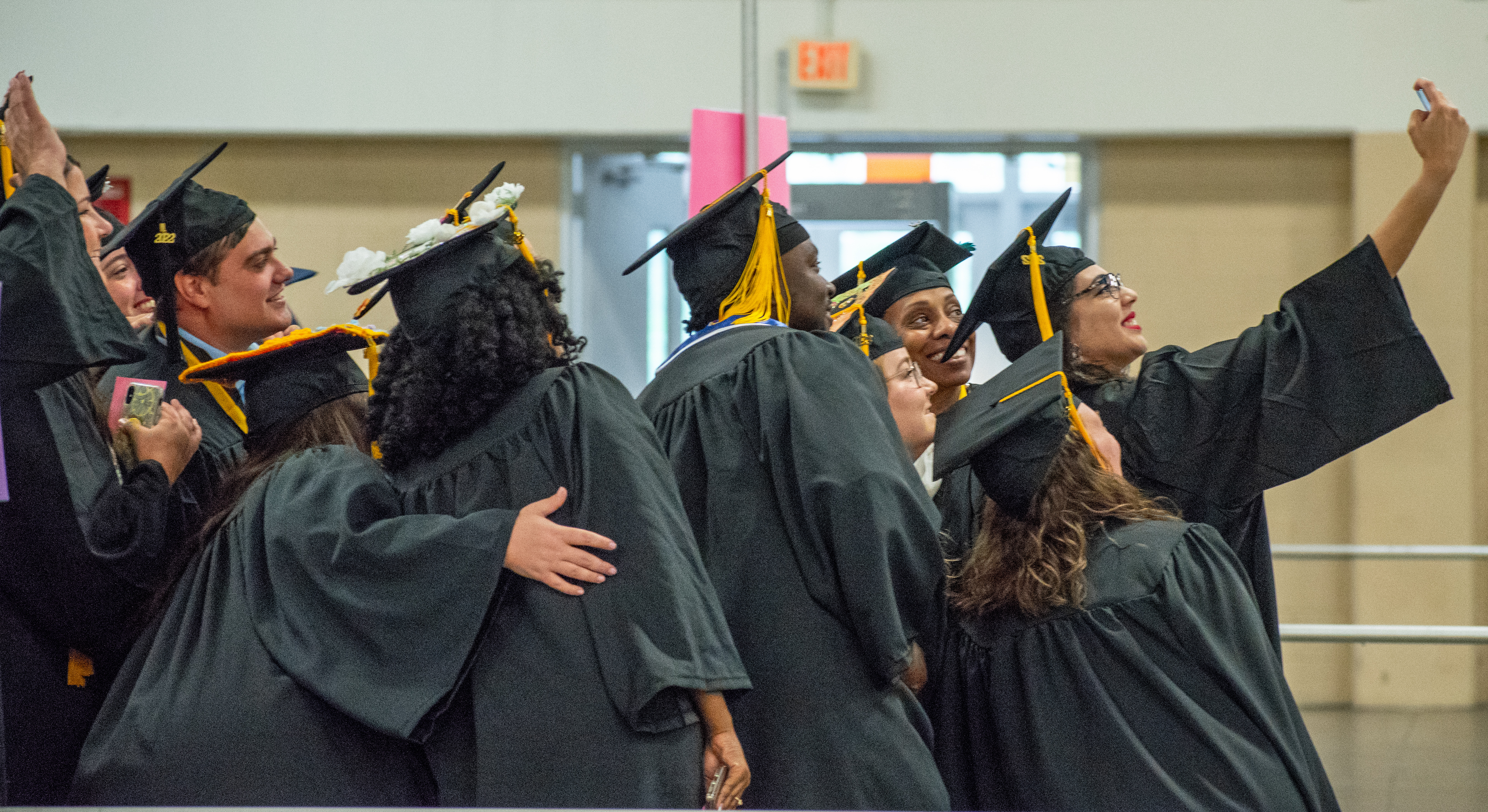 A photo taken in profile of a group of graduates posing for a selfie being taken by the graduate on the right.