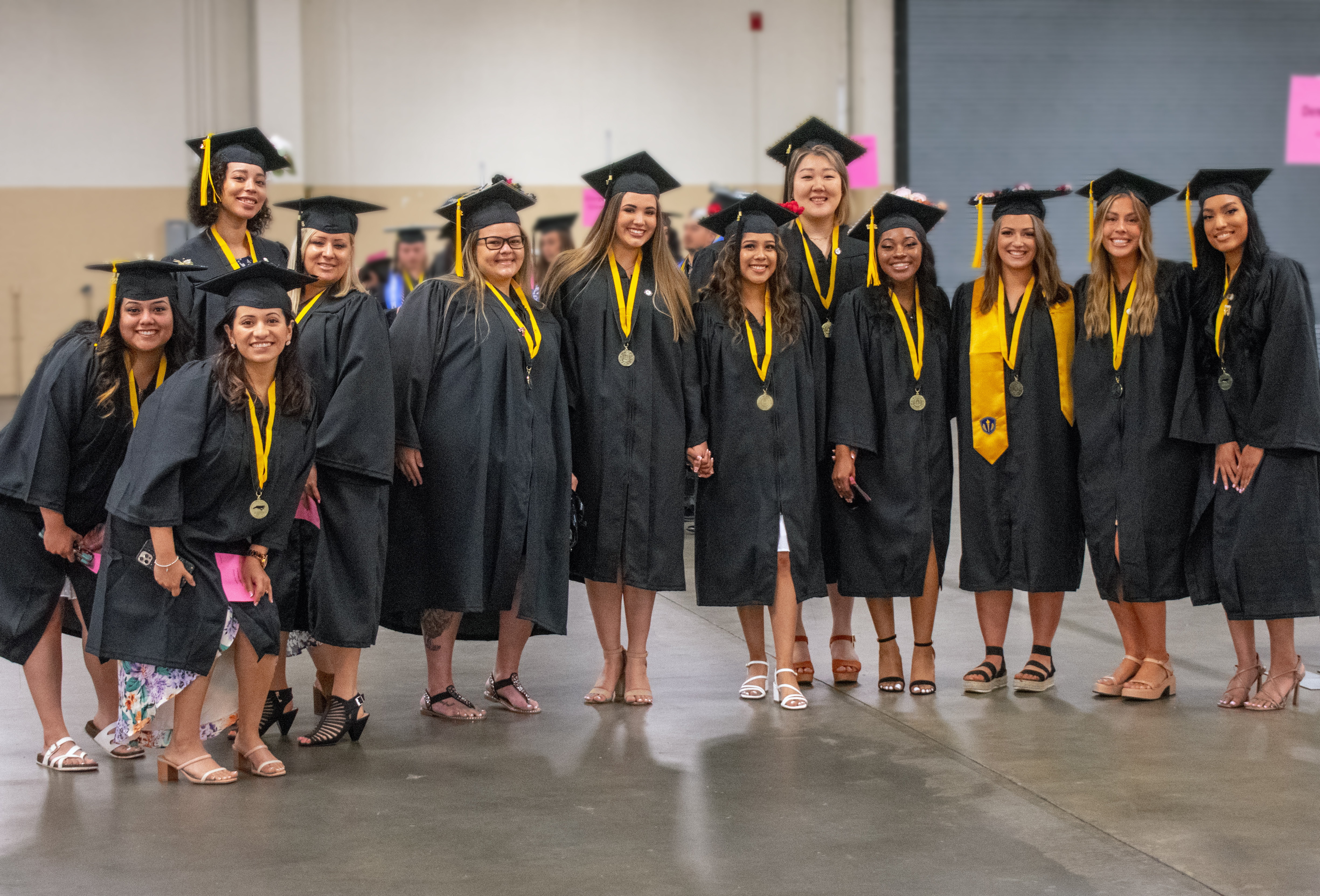 A group of graduates pose for a photo being taken by someone out of the frame.