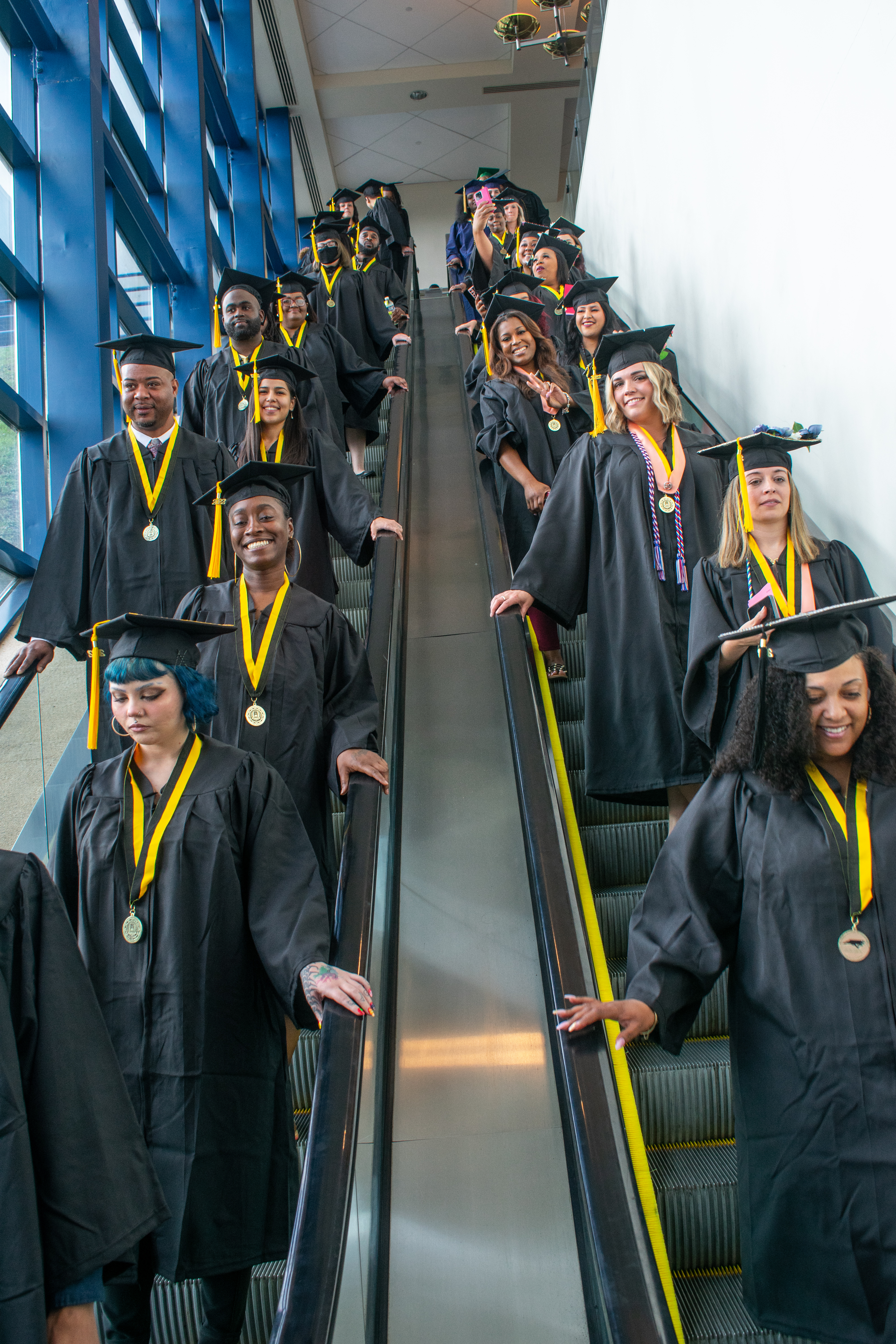 Graduates descend two escalators before graduation.