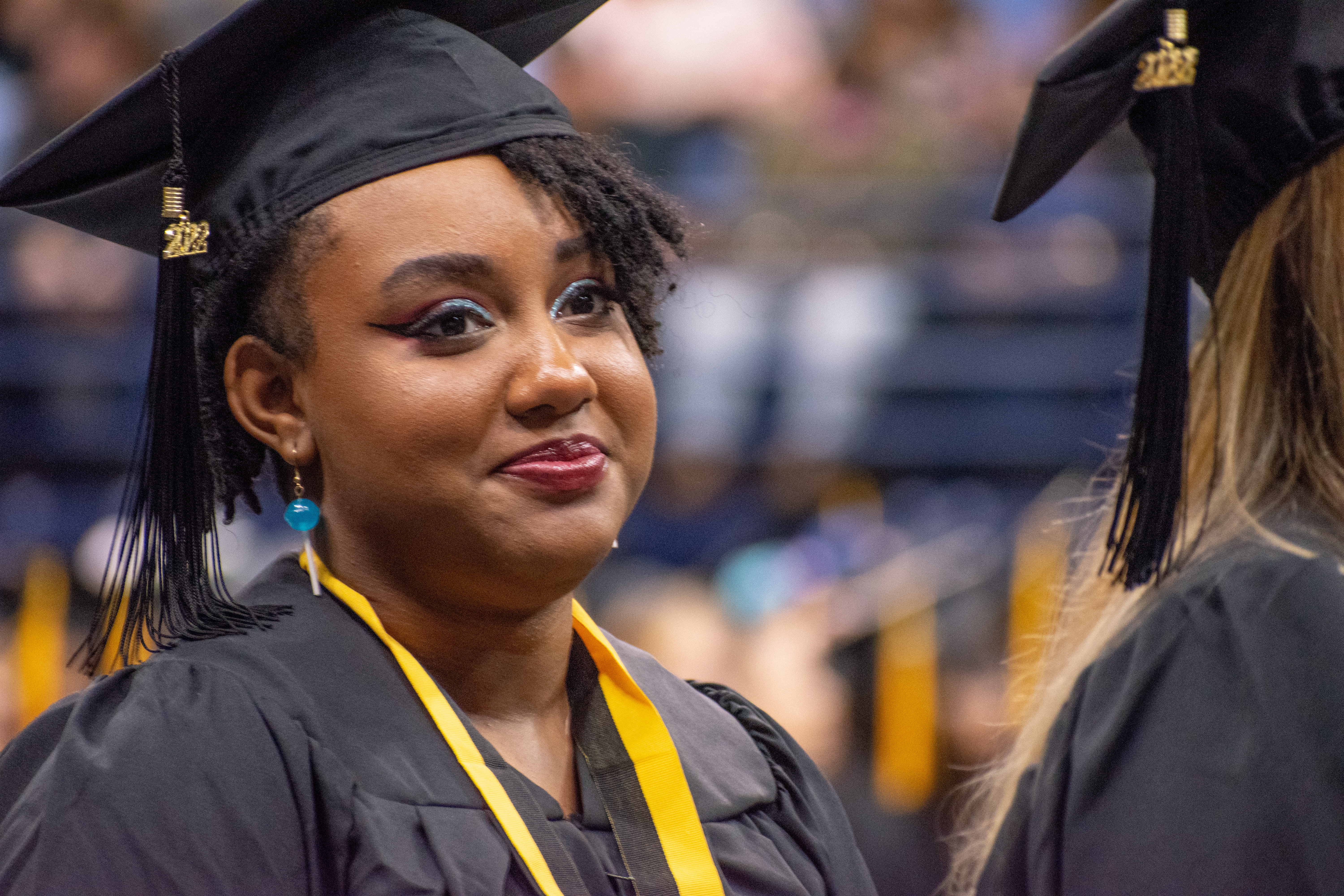 A graduate smiles as she looks up at the stage.