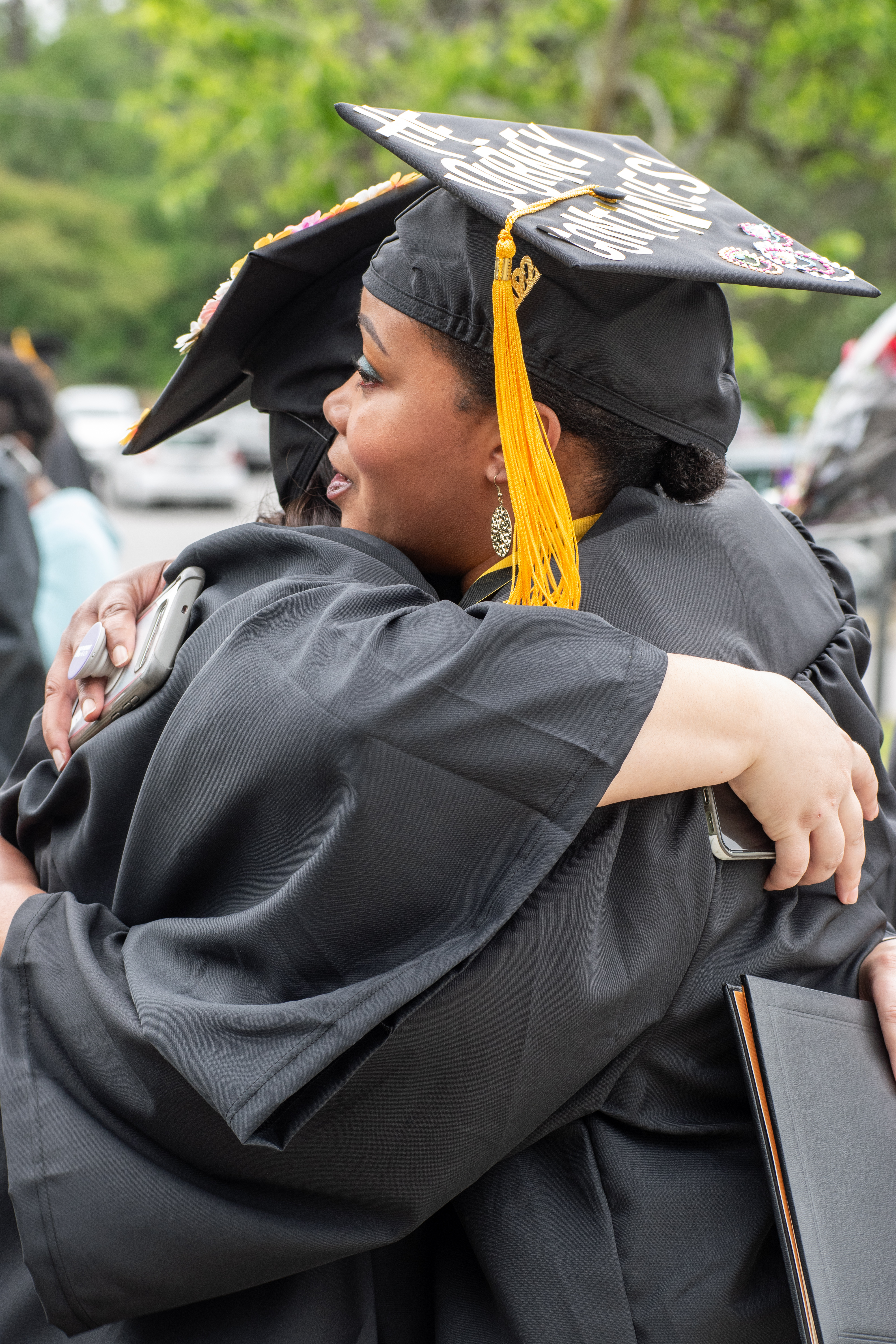 Two graduates hug outside after graduation.