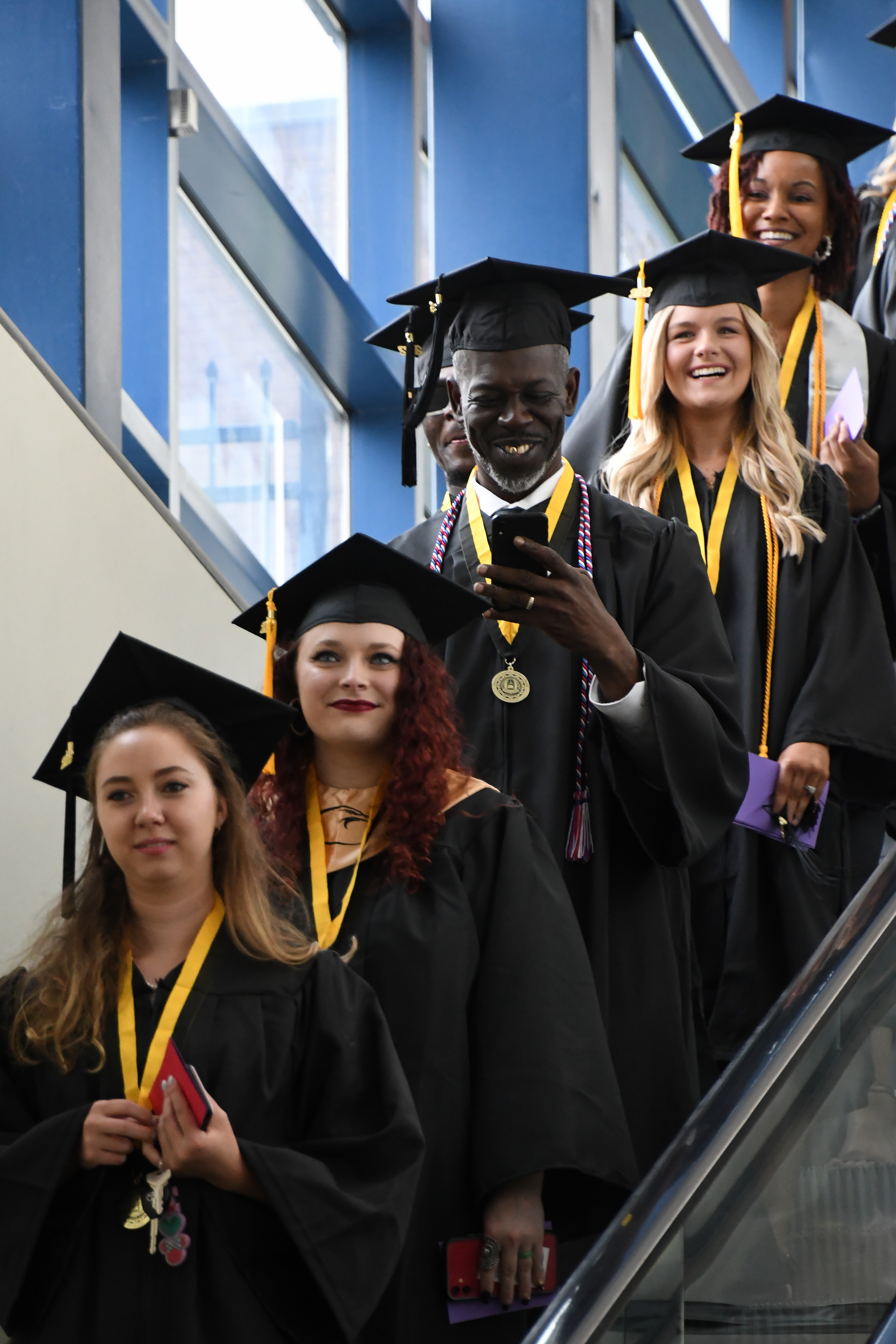 A group of graduates comes down the escalator.