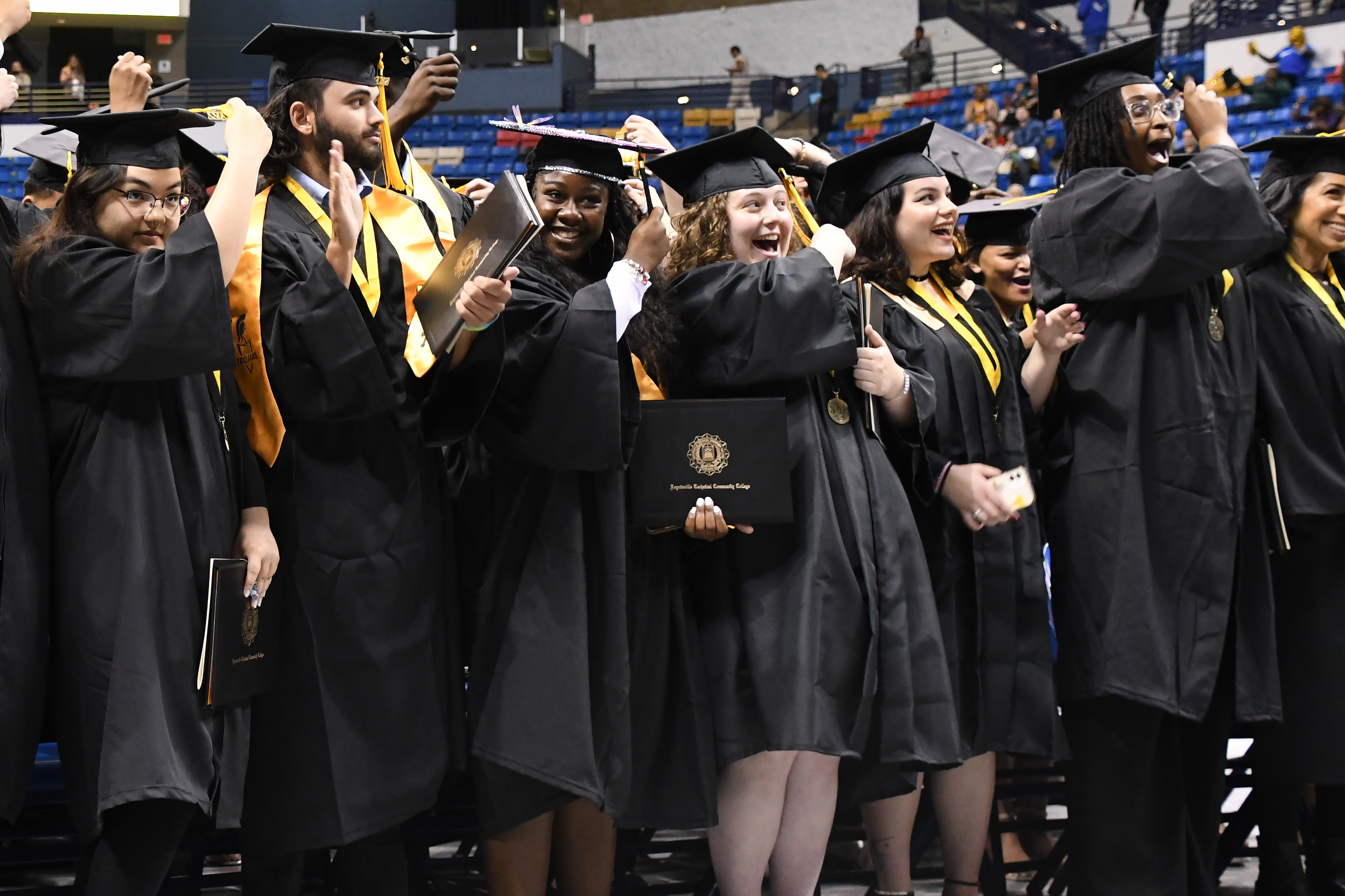 A group of standing graduates celebrate as they turn their tassels at graduation.