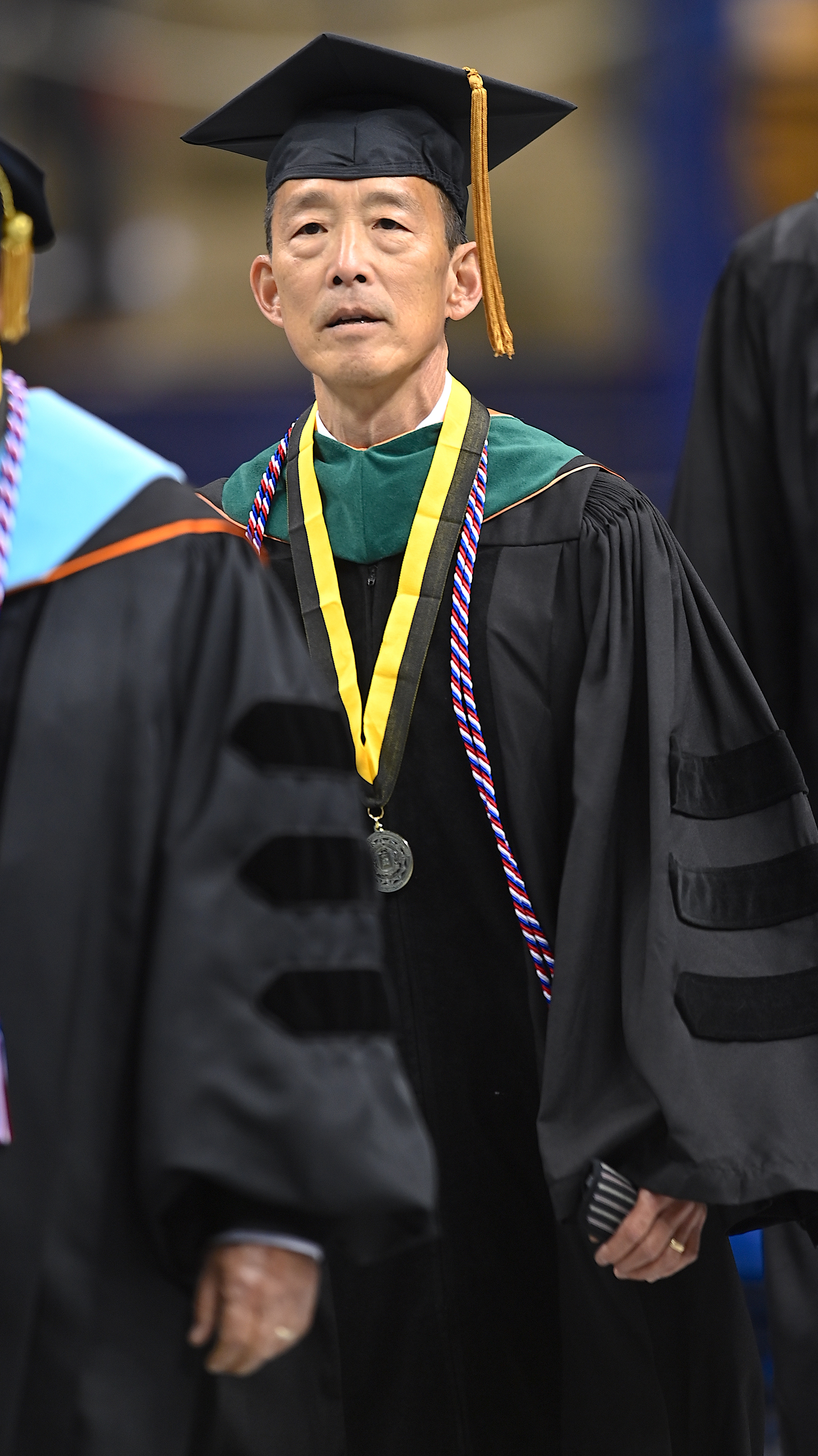 Dr. Y. Sammy Choi, dressed in doctoral regalia, walks to the stage at graduate.
