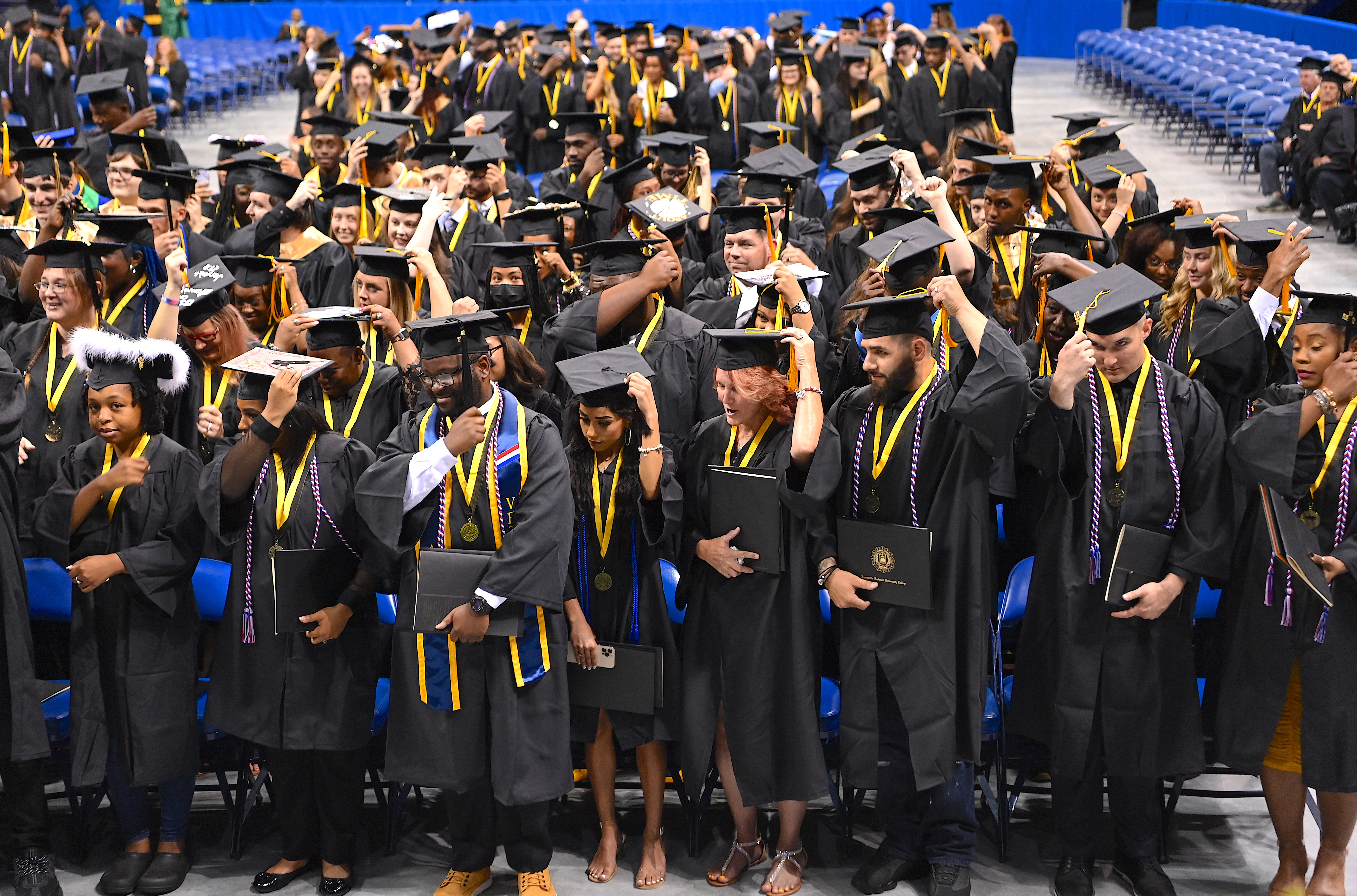 A group of graduates, standing, turn their tassels.