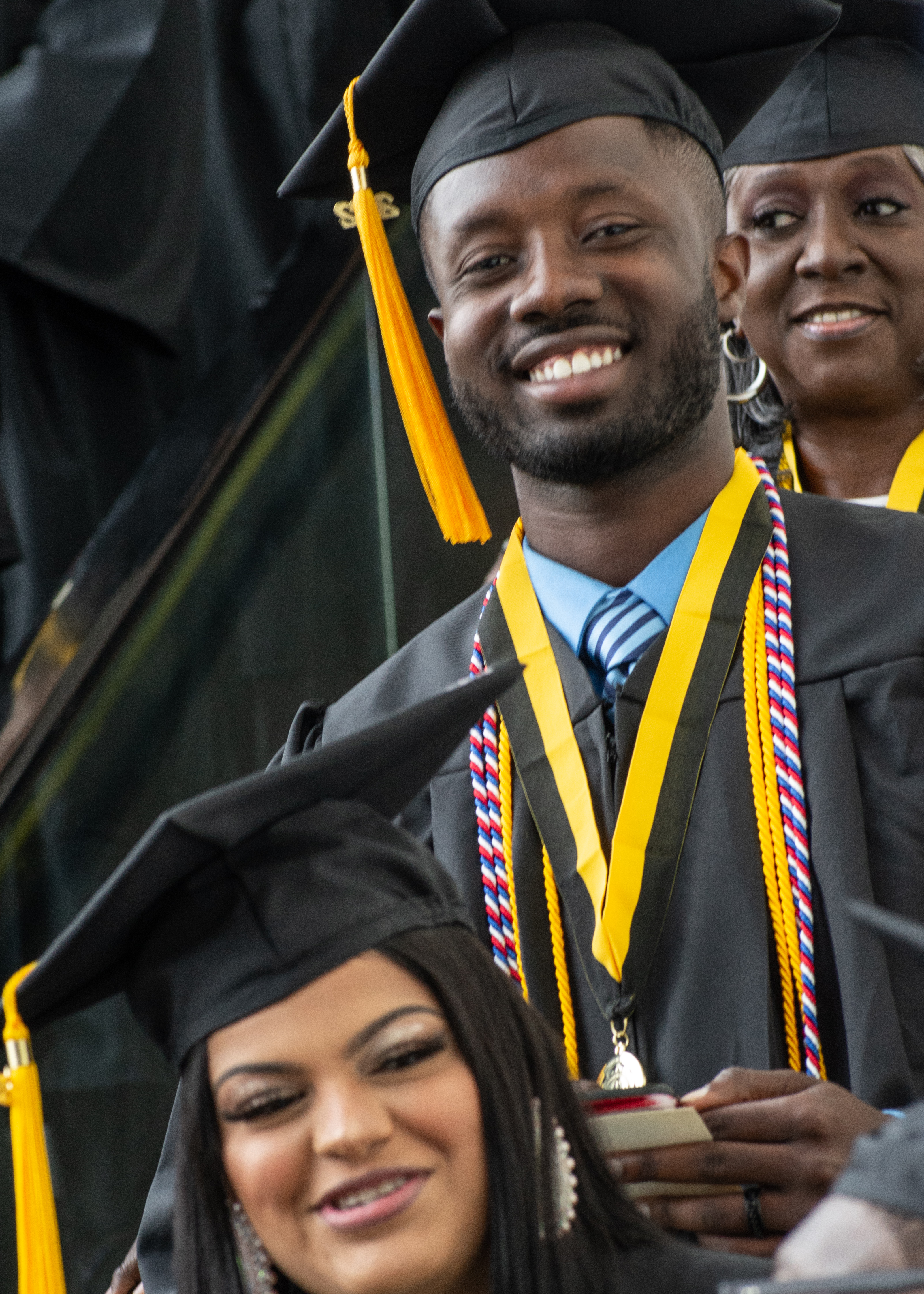 A graduate descending the escalator smiles for the camera.