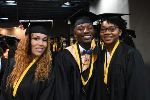 Three graduates pose together for the camera in the tunnel before walking into the arena.