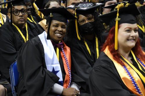 A graduate wearing a personalized stole with red, white and blue blocks and a blue star, symbolizing the flag of Panama, smiles at the camera.
