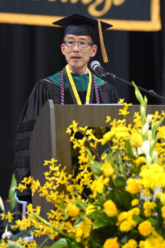 Dr. Y. Sammy Choi, dressed in doctoral regalia, speaks at the podium.