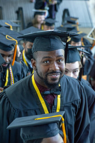 A graduate wearing a dark bow tie smiles for the camera after graduation.