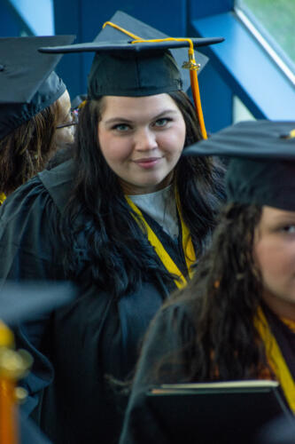 A graduate looks up into the camera as she comes up the escalator after graduation.