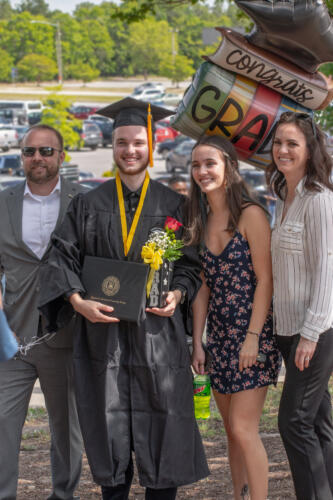 A graduate and his loved ones pose for a photo outside.