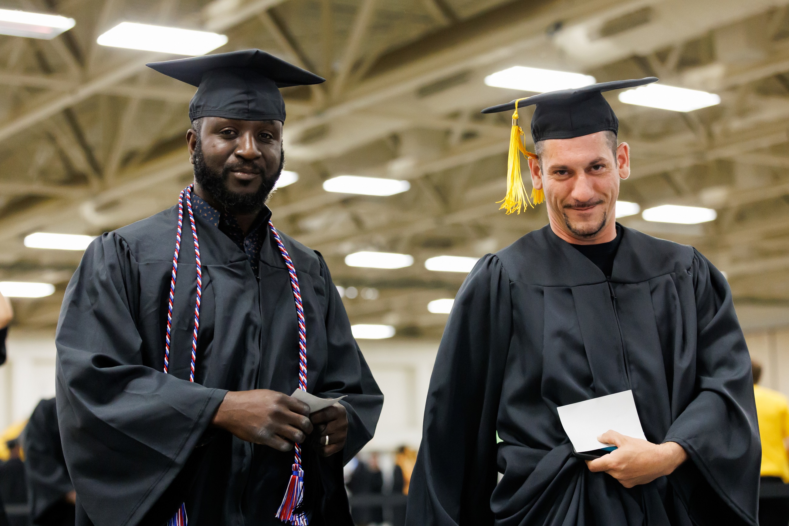 Two graduates smile at the camera.