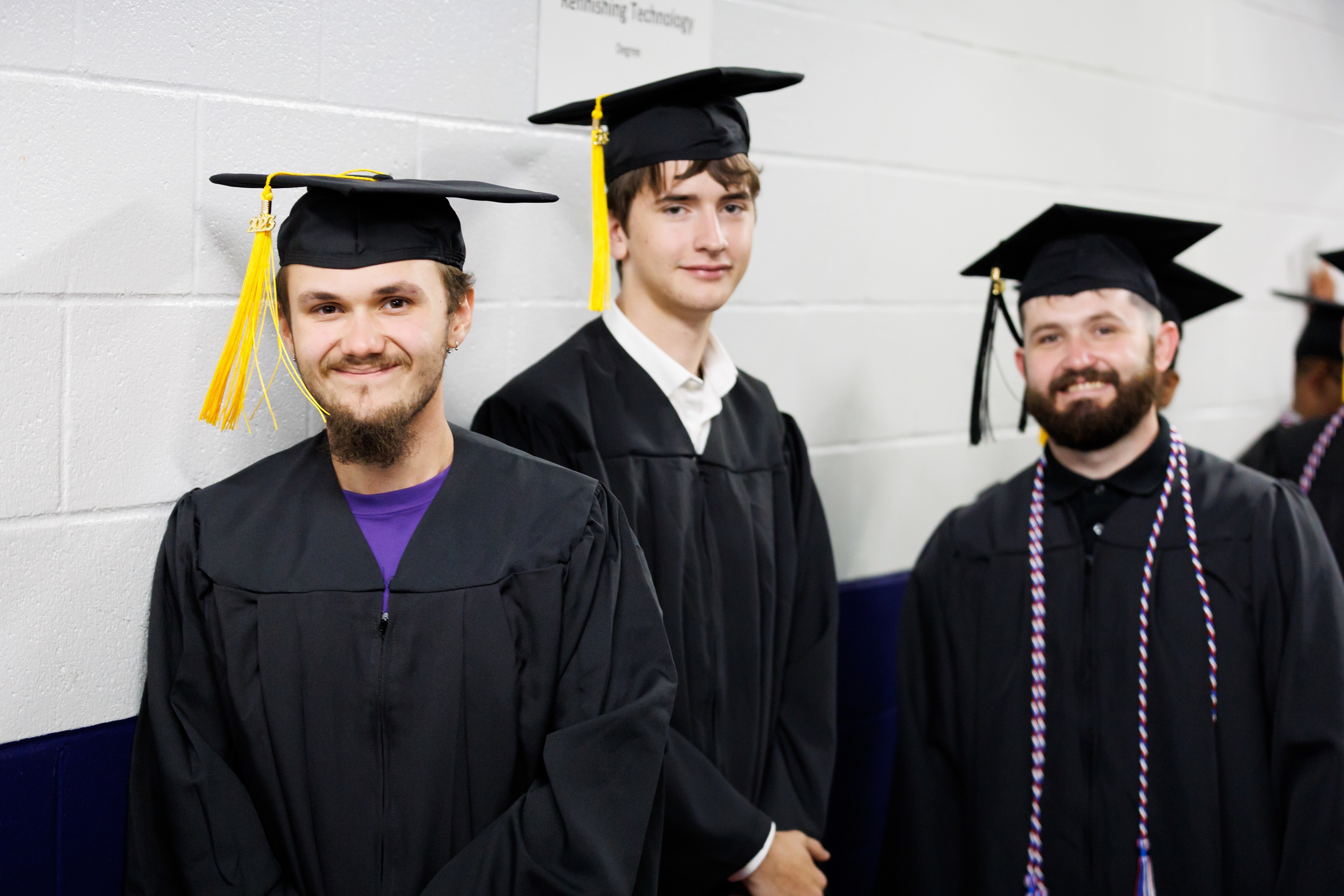A group of graduates smile at the camera in the hallway.