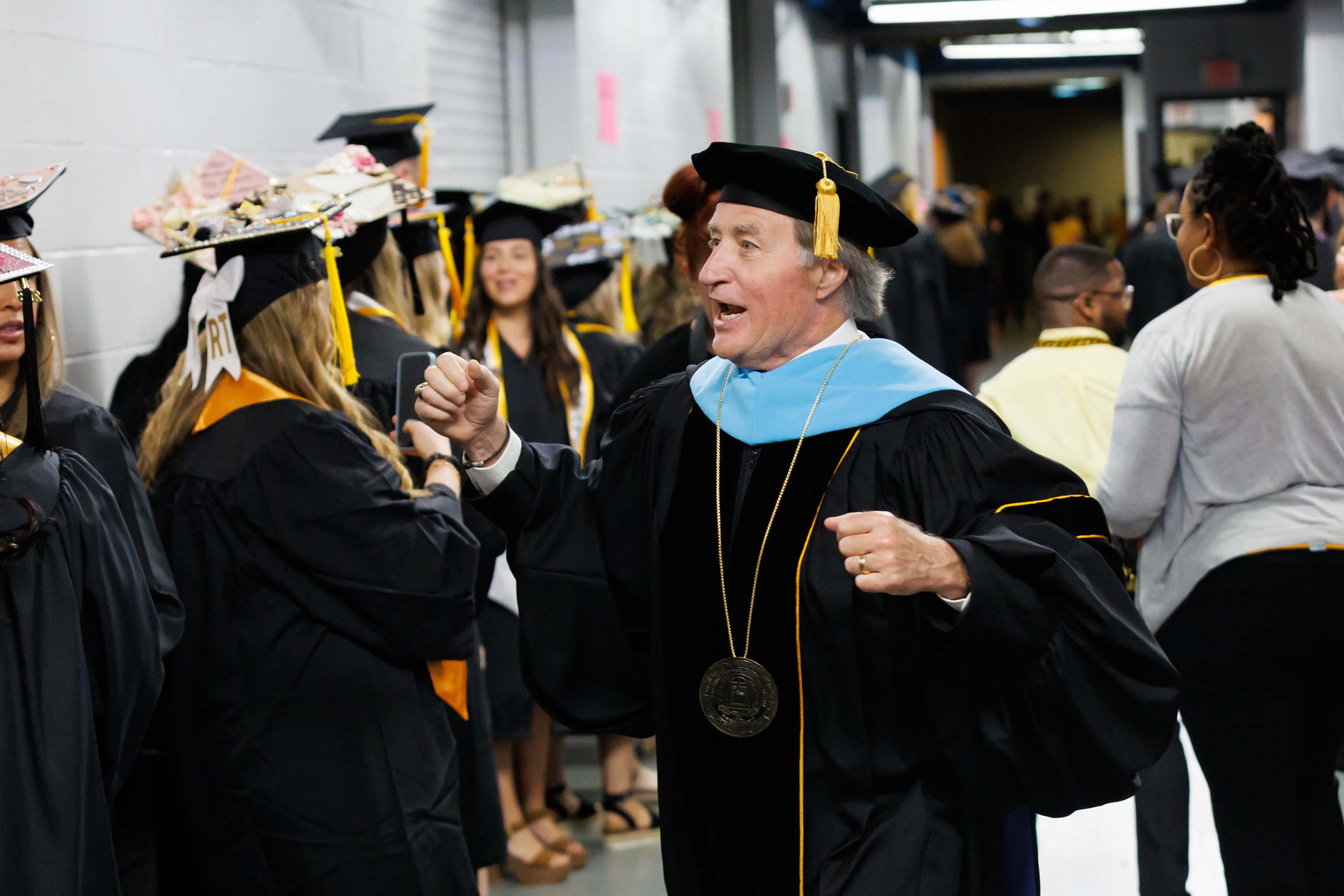 Dr. Mark Sorrells talks excitedly with graduates lined up in the hallway of the Crown.