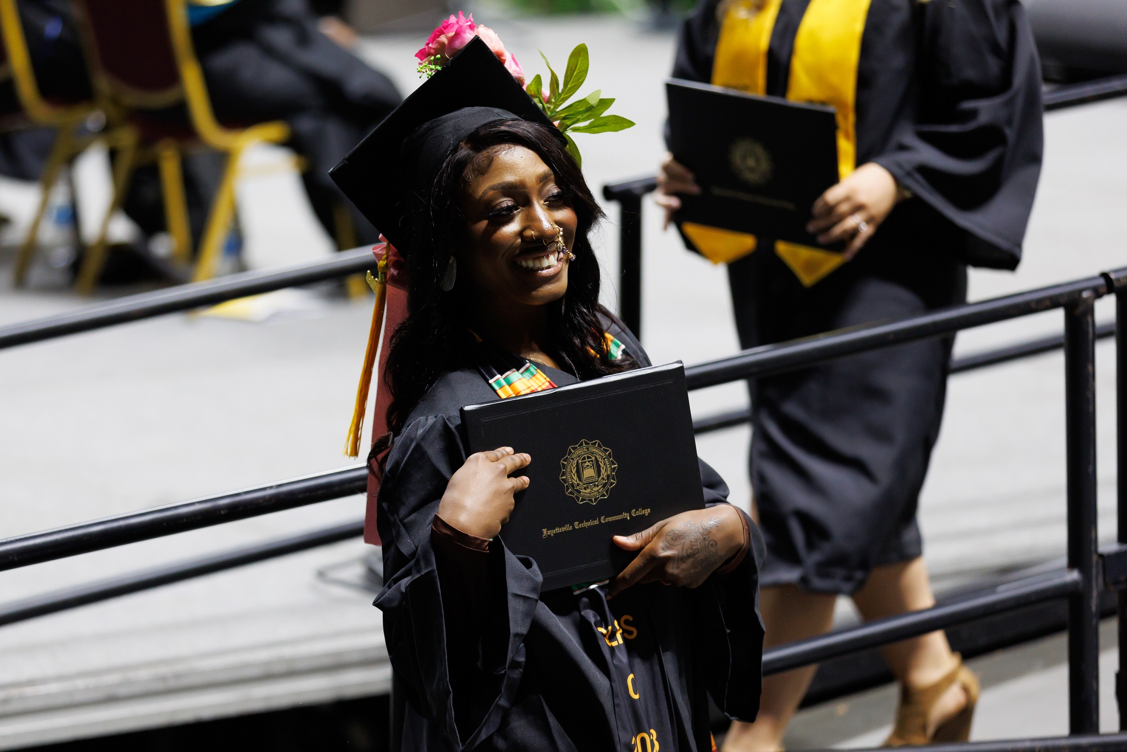 A graduate shows off her diploma folder to the crowd as she exits the stage.