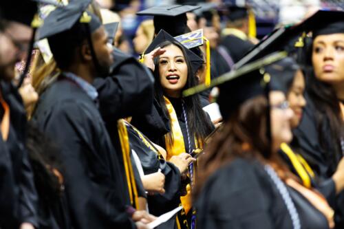 A graduate shields her eyes as she looks up into the crowd from the Crown floor.
