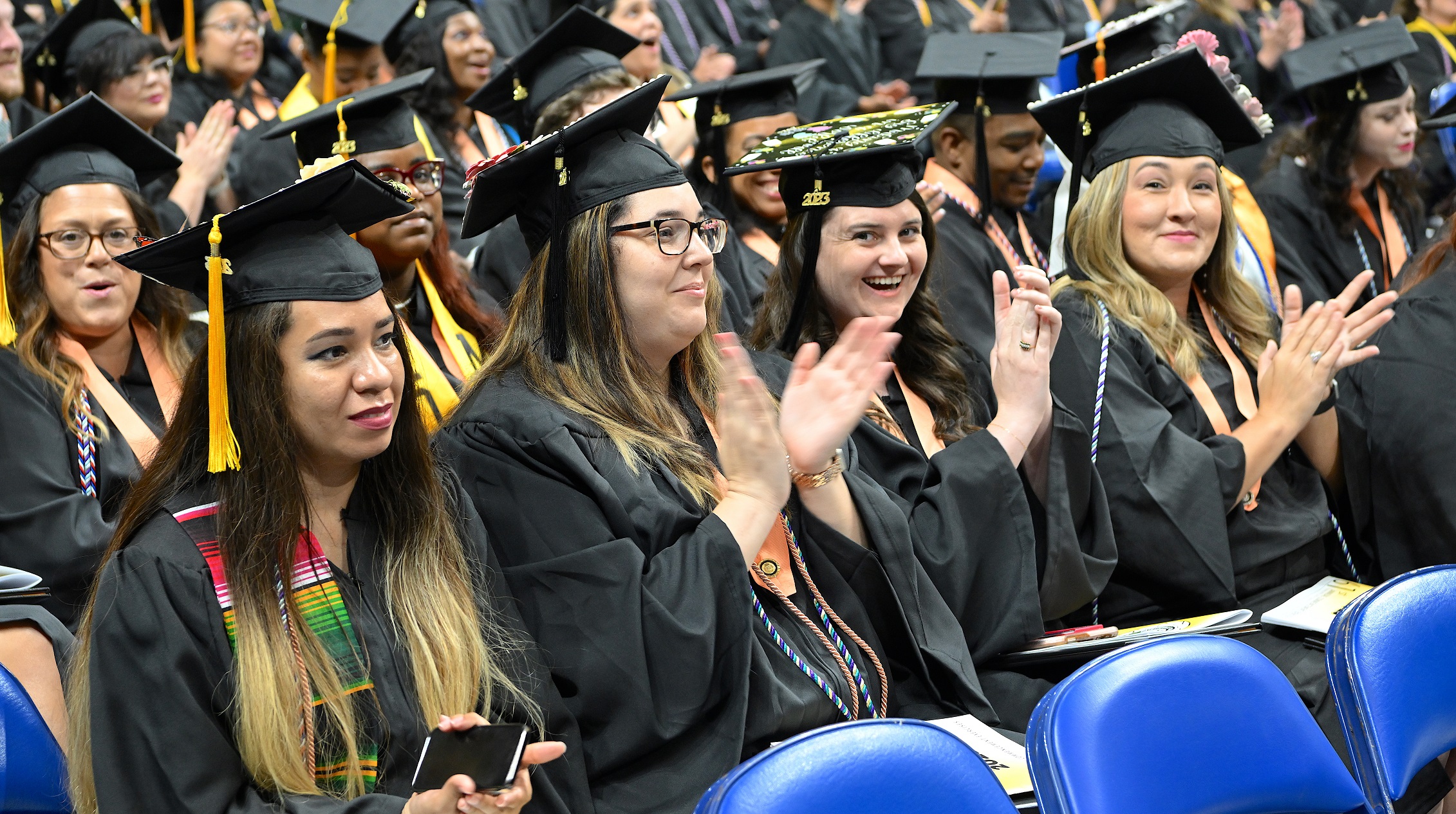 A row of graduates clap during the commencement ceremony.