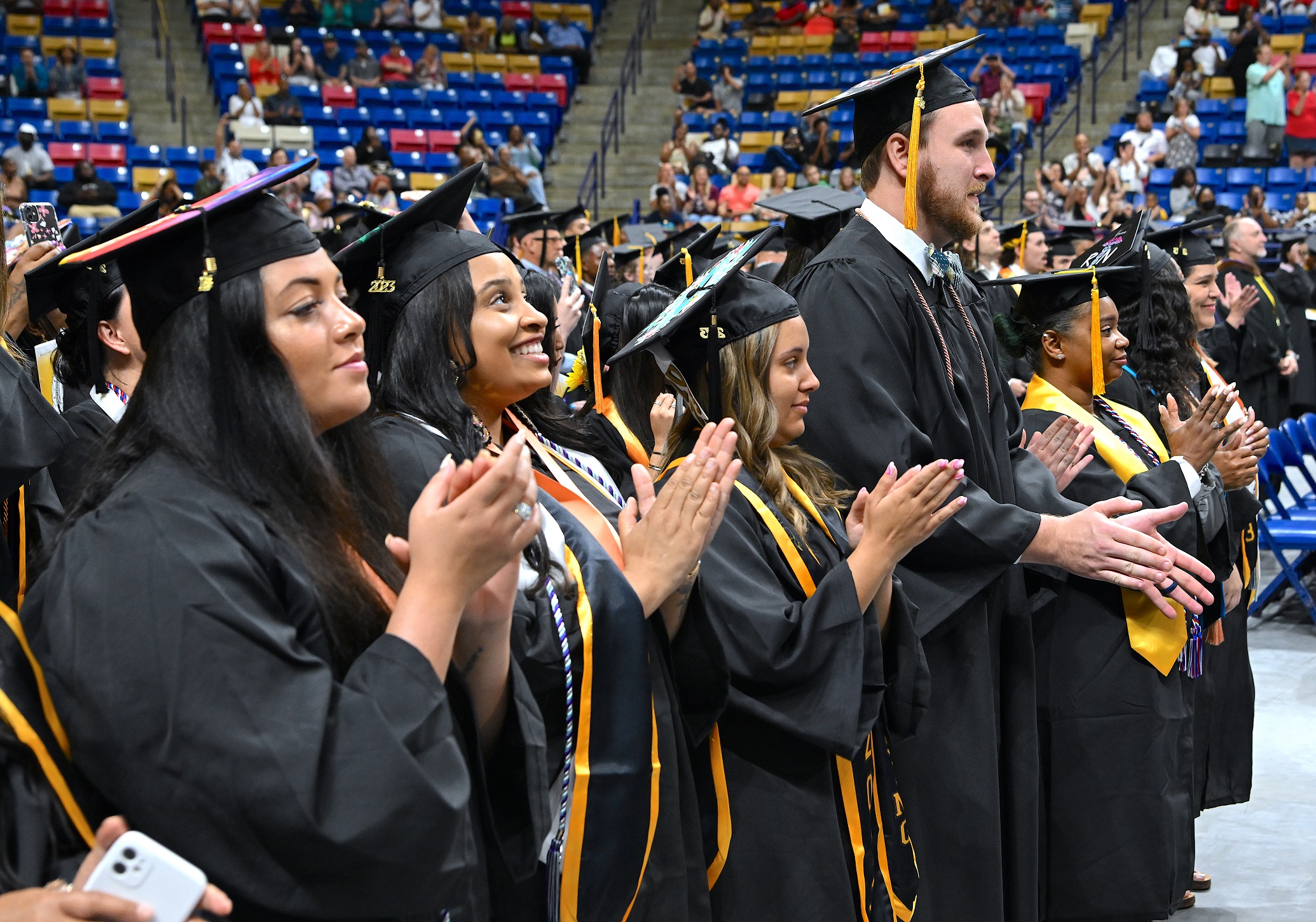 Graduates stand up and clap during the commencement ceremony.