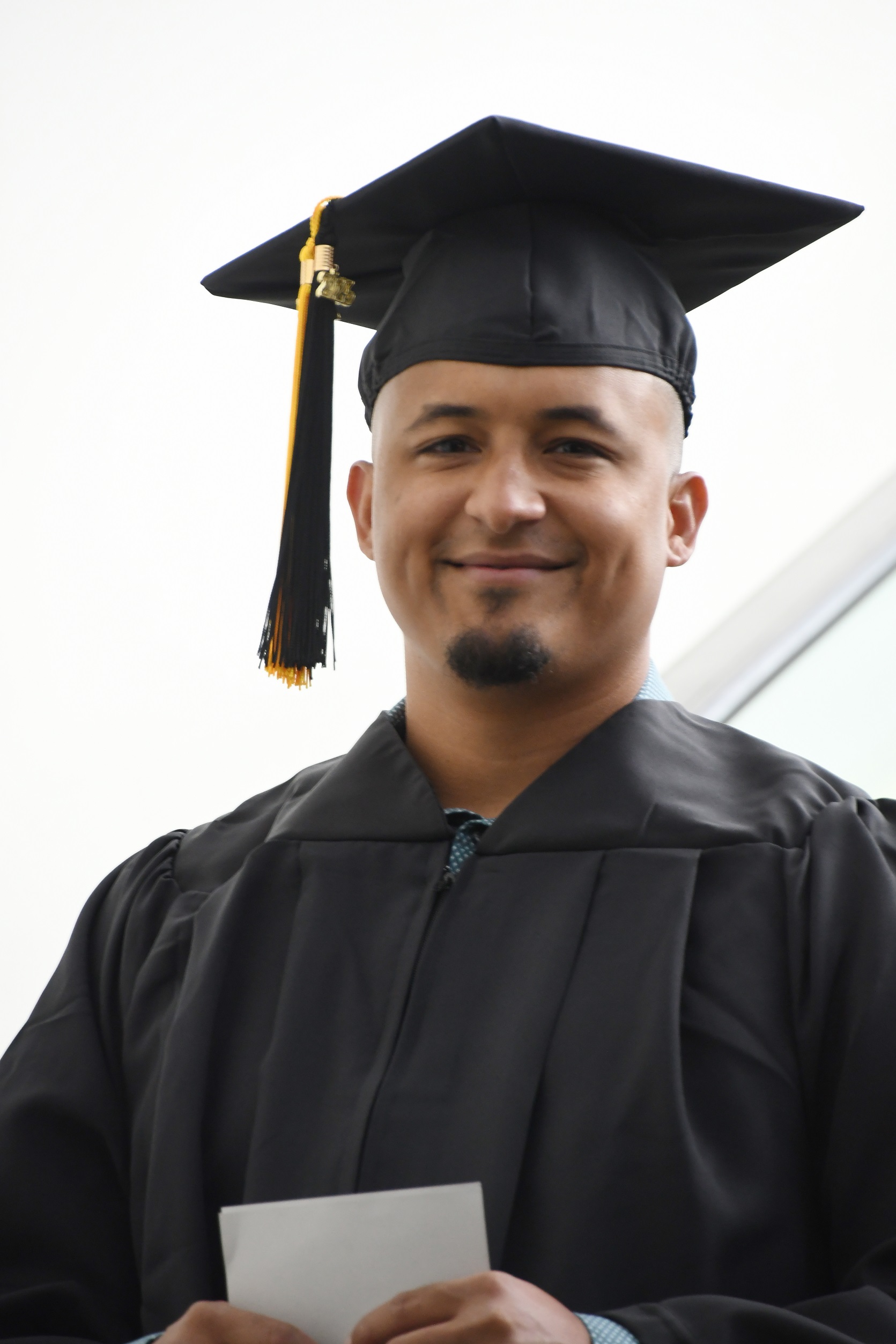 A close-up photo of a graduate in cap and gown.
