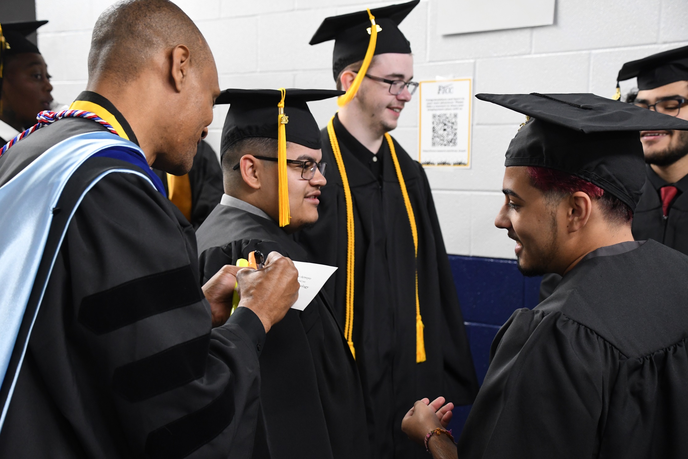 A faculty member writes on a graduate's name card.