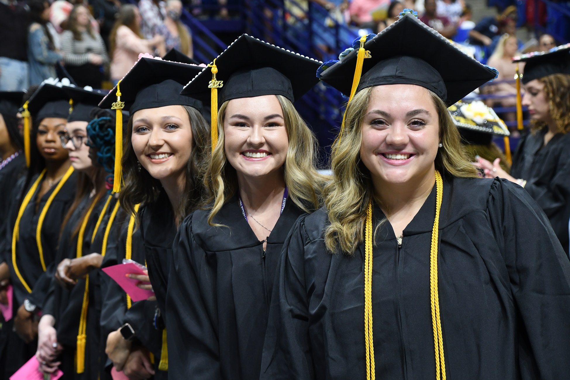 A group of graduates smiles at the camera.