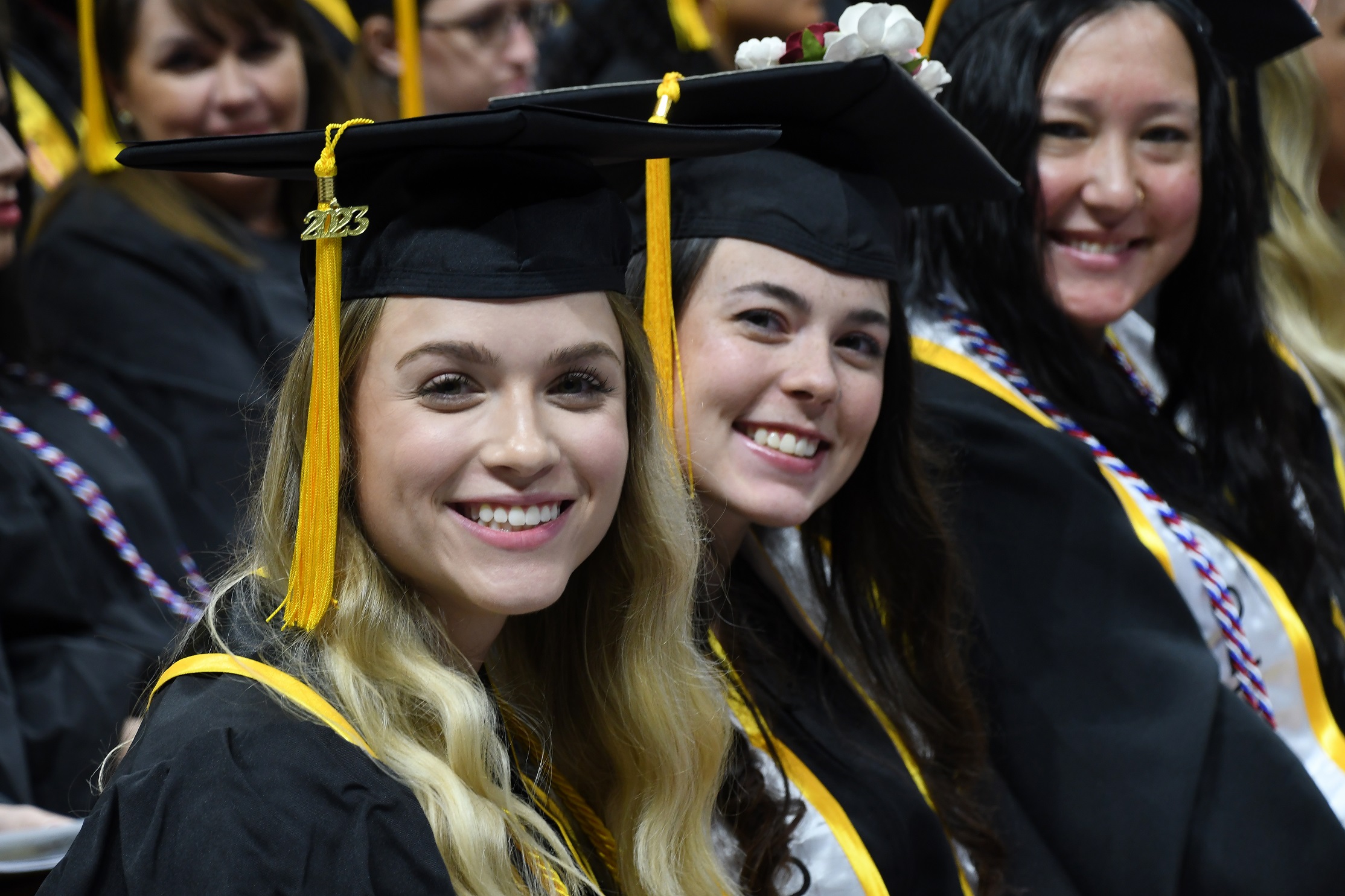 Graduates sitting in a row smile at the camera.