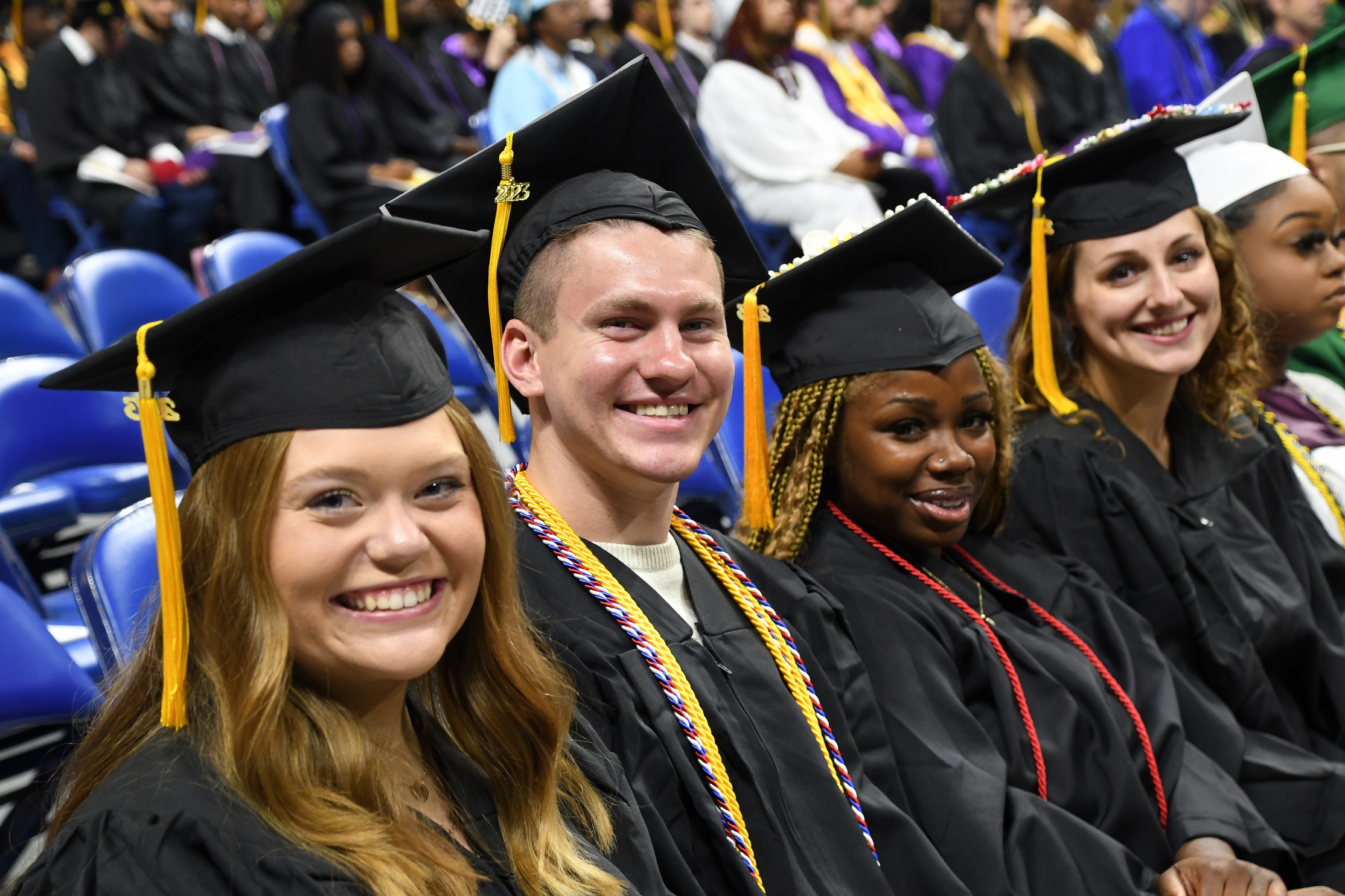Graduates sitting in a row smile at the camera.