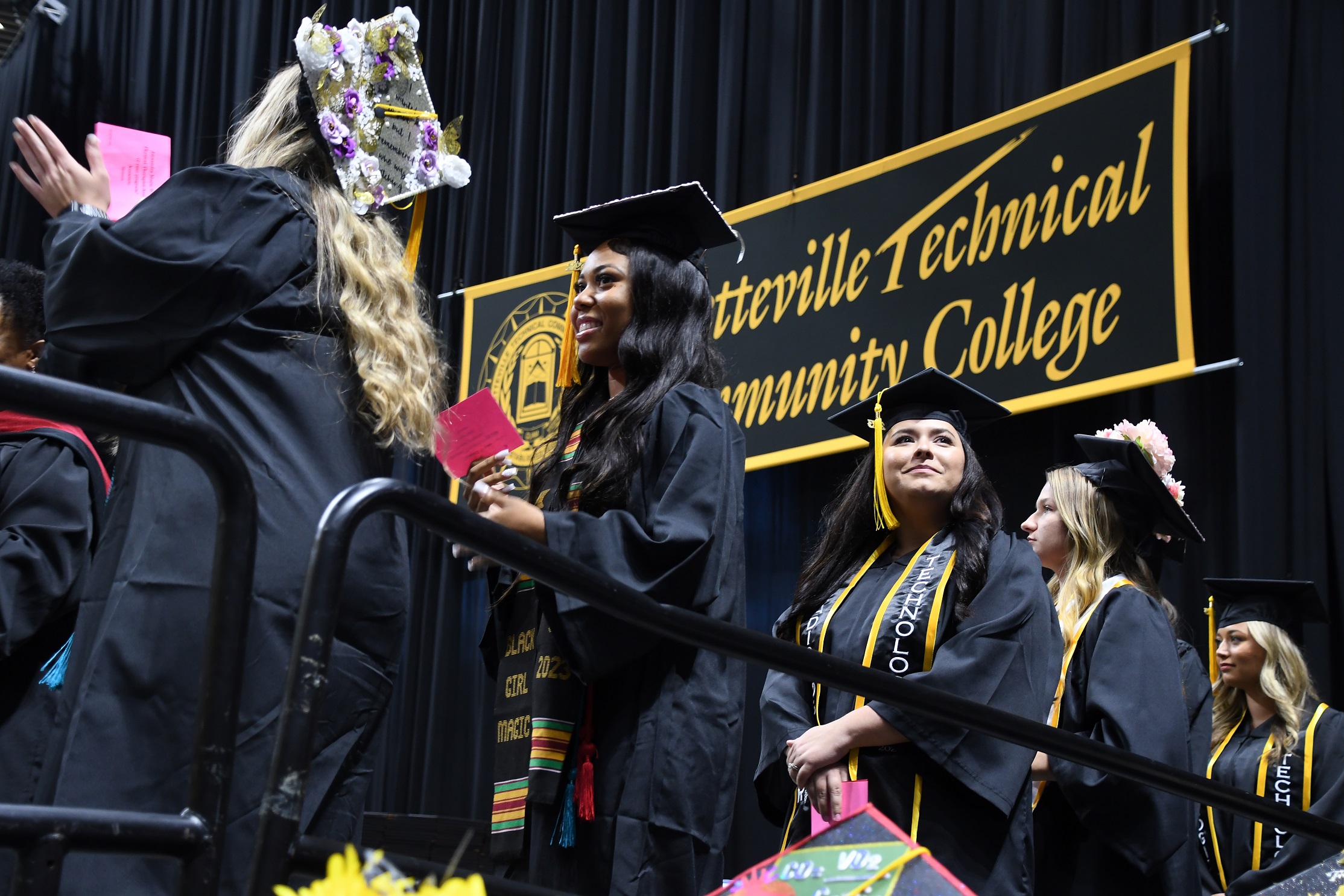 Graduates wait in a line a the edge of the stage.