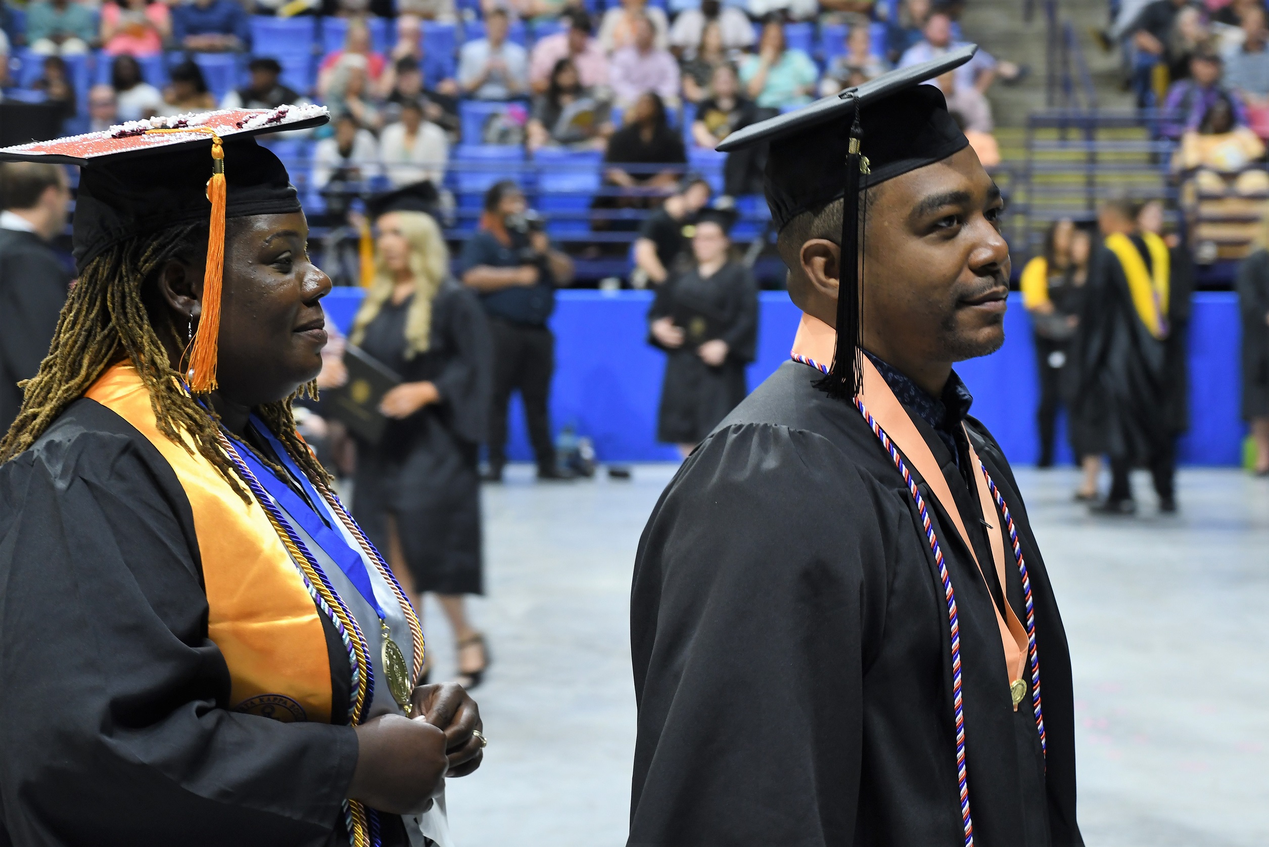 Graduates walk in a line to the stage.