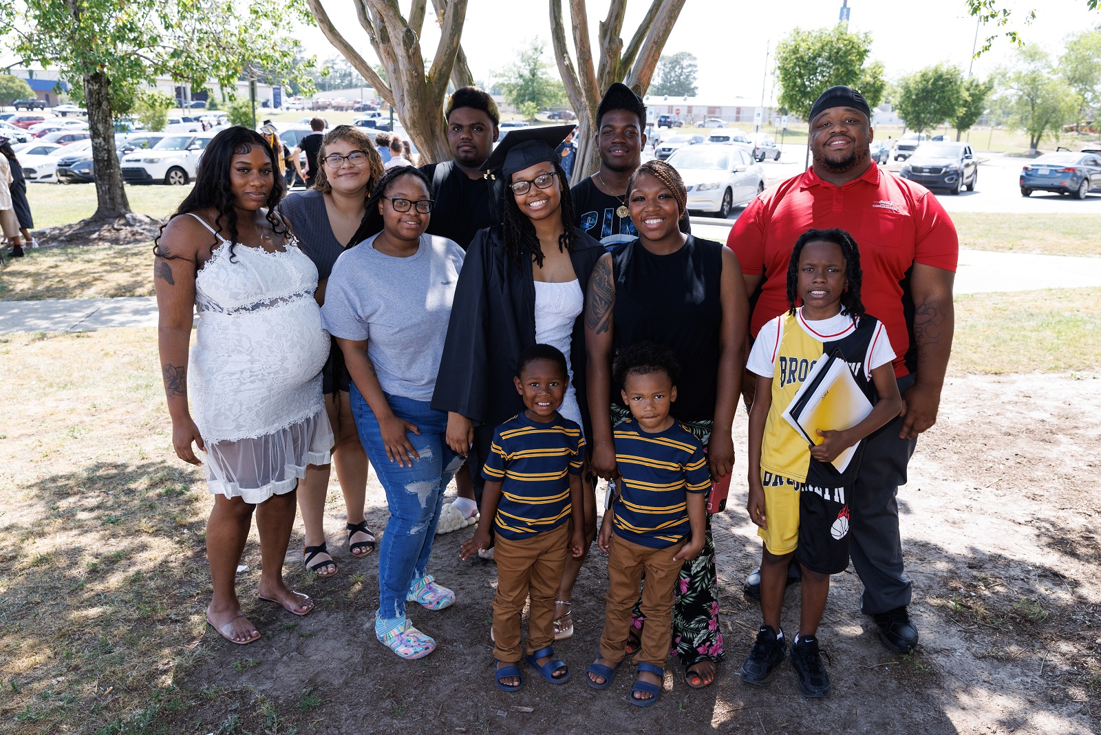 A graduate poses with a group of her loved ones in front of a tree outside of the Crown.