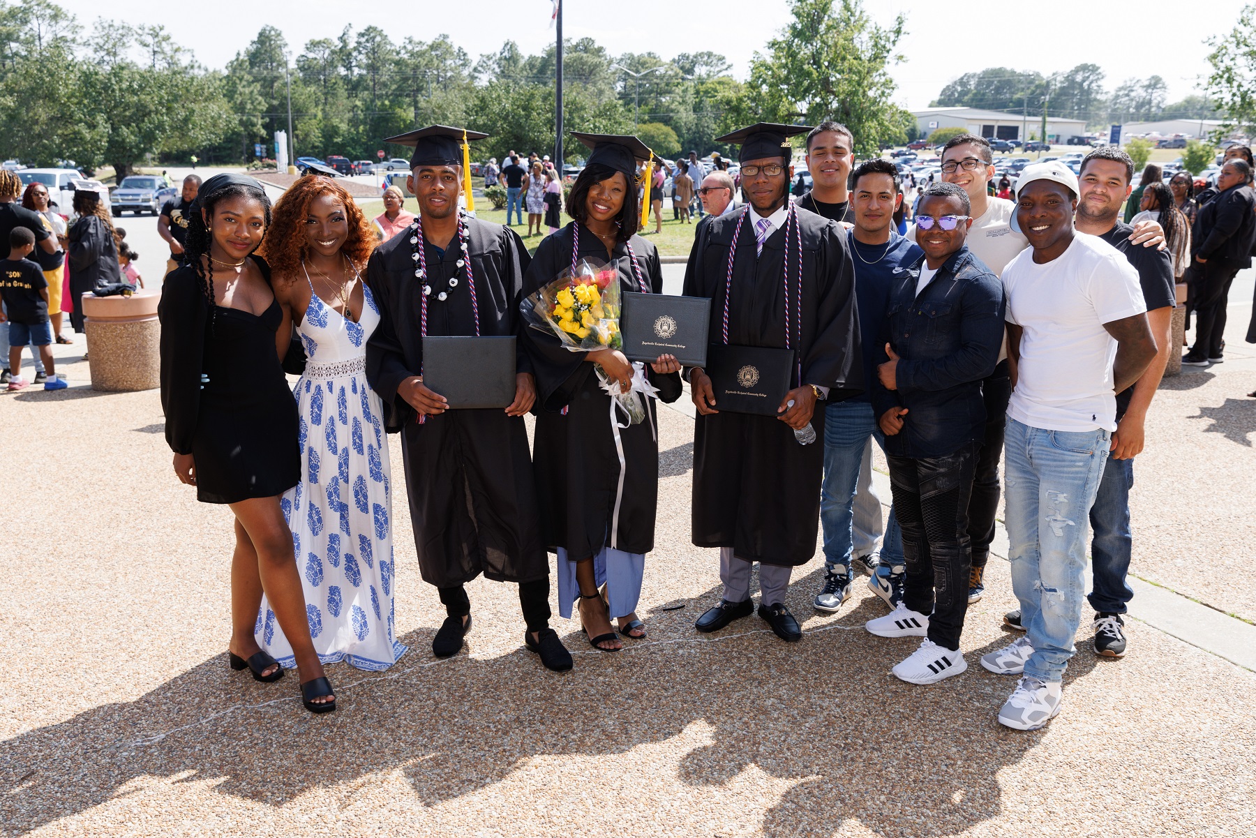 Three graduates pose for a photo with loved ones outside of the Crown.