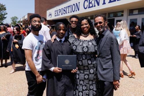 A graduate and his family pose together outside the Crown Expo doors.