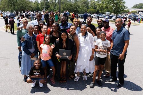 A graduate and a large group of her loved ones stand together for a photo outside of the Crown. 