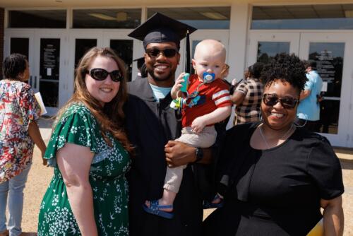 A graduate poses for a photo with his family outside of the Crown.