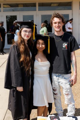 Two graduates pose with a man in front of the Crown doors.