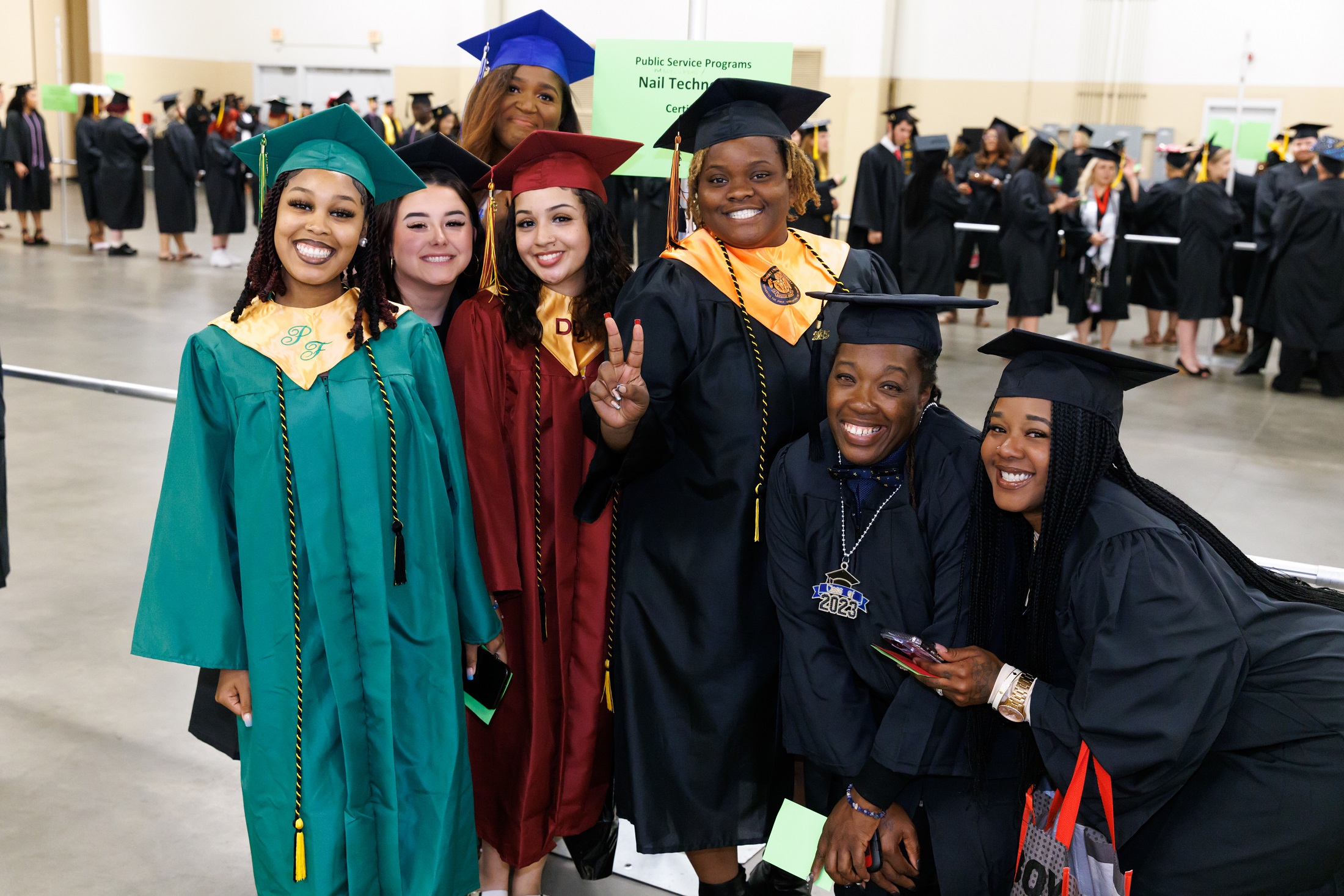 A group of graduates wearing robes in various high school colors pose for a photo.