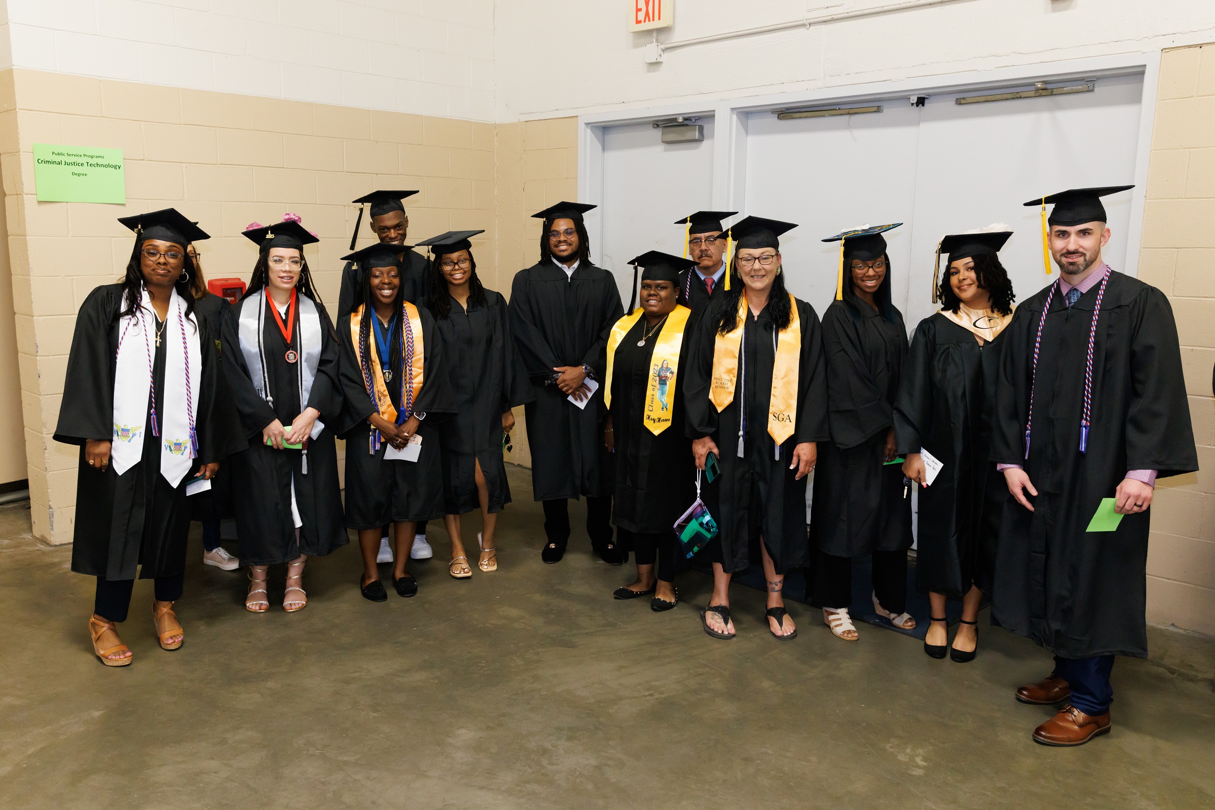 A group of graduates pose for a photo in the corner of the staging area.