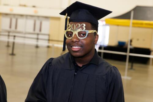 A graduate wears glasses that say 2023 on top of the frames.