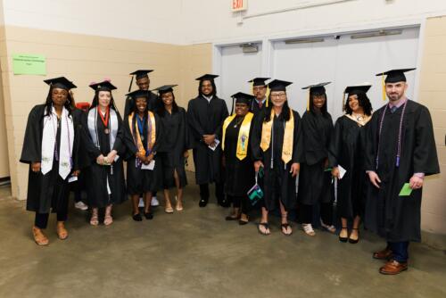 A group of graduates pose for a photo in the corner of the staging area.