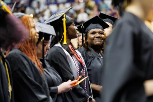 A row of graduates look up into the crowd while waiting to take their seats.