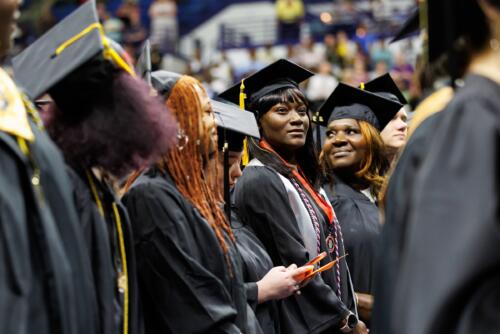 A row of graduates look up into the crowd while waiting to take their seats.