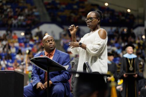 A sign language interpreter stands at a lectern as she signs on stage.