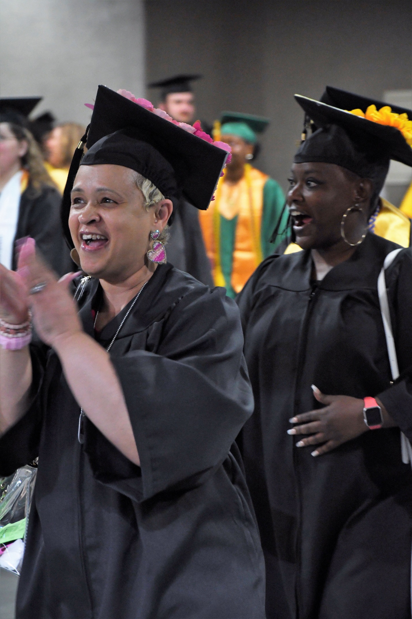 A close-up photo of two graduates cheering as they walk into the Crown.