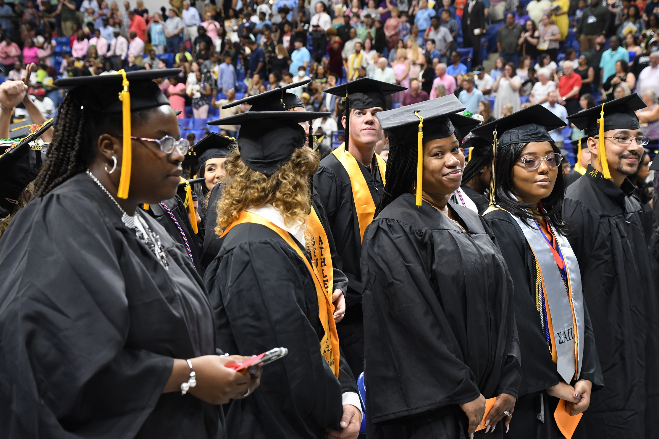 Graduates stand in a row before taking their seats for the commencement ceremony.