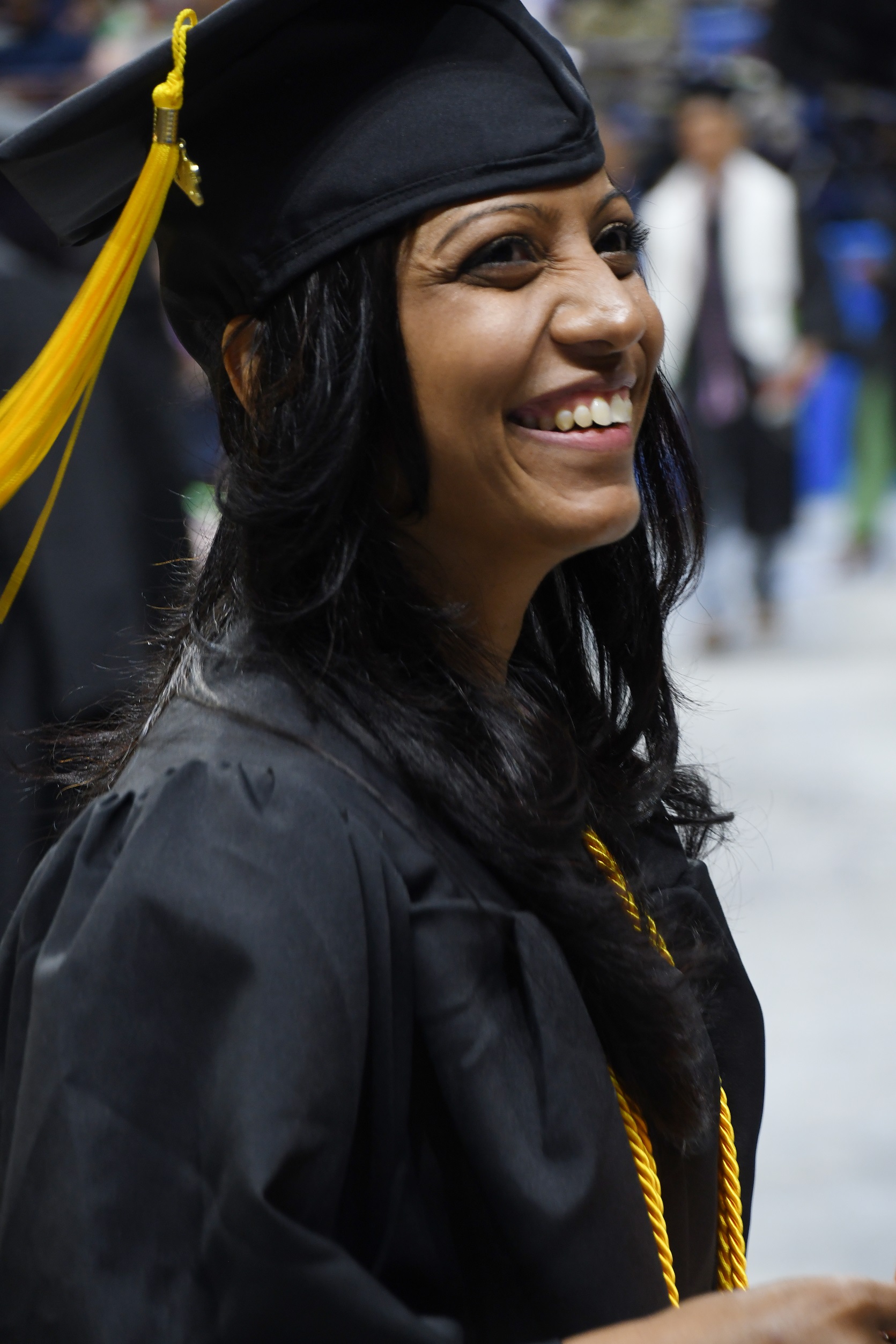 A graduate, shown in profile, smiles at the crowd.