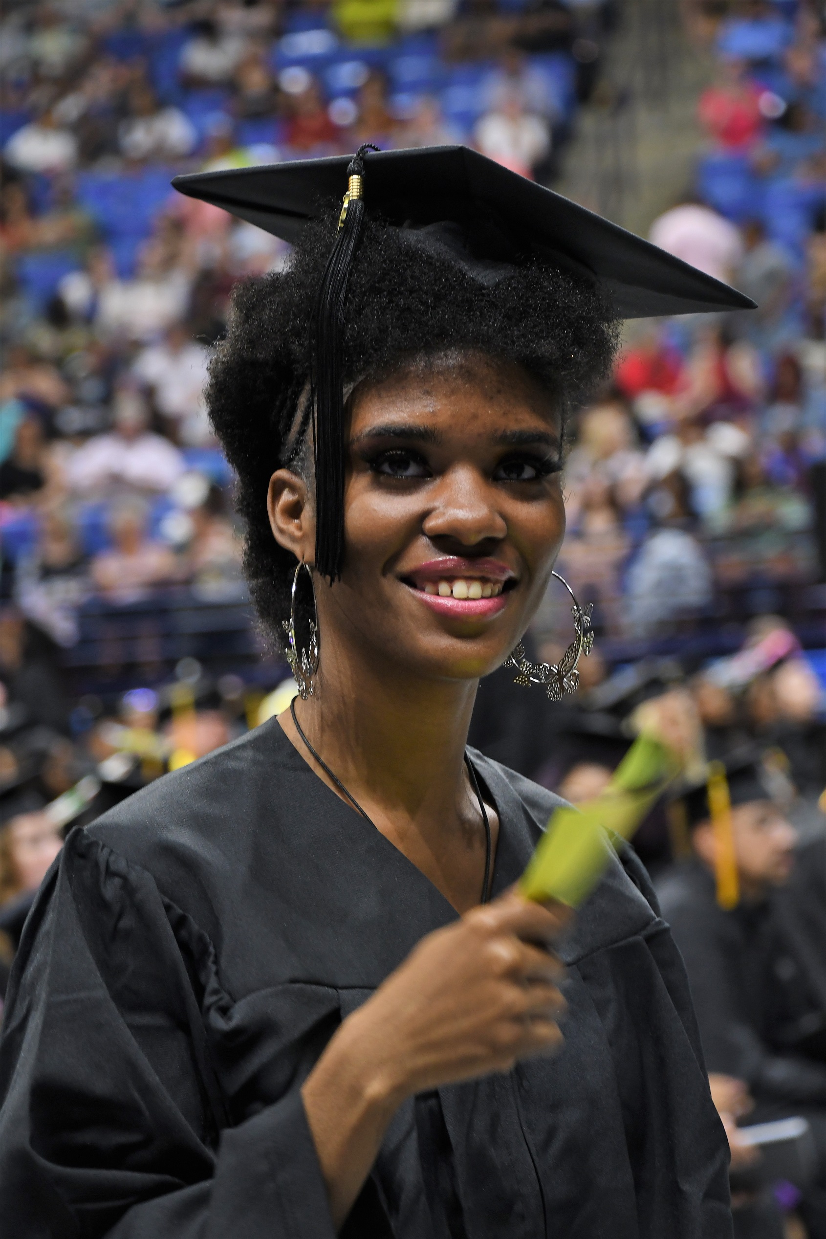 A graduate smiles at the camera as she walks.